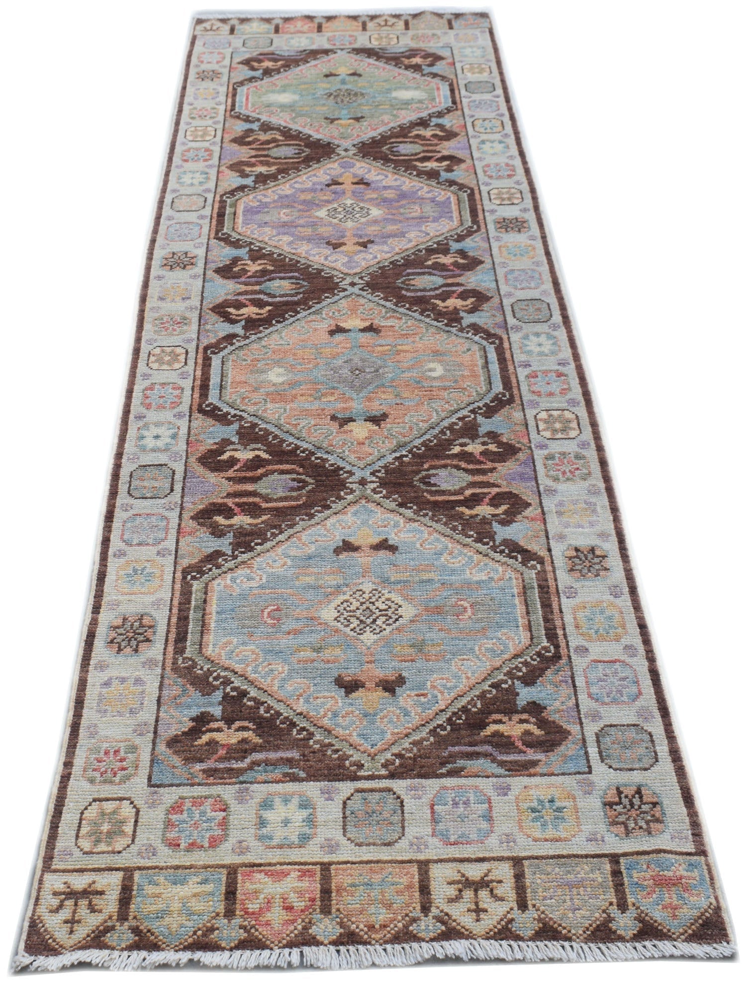 A handmade Afghan Oushak runner rug featuring a traditional geometric pattern in muted colors.