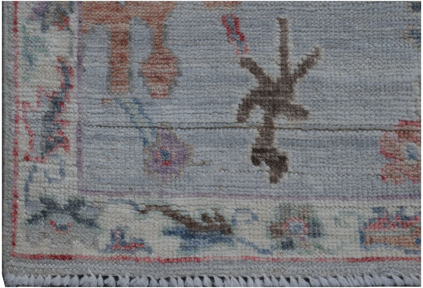 A handmade Afghan Oushak runner featuring a traditional floral pattern in soft, muted tones.