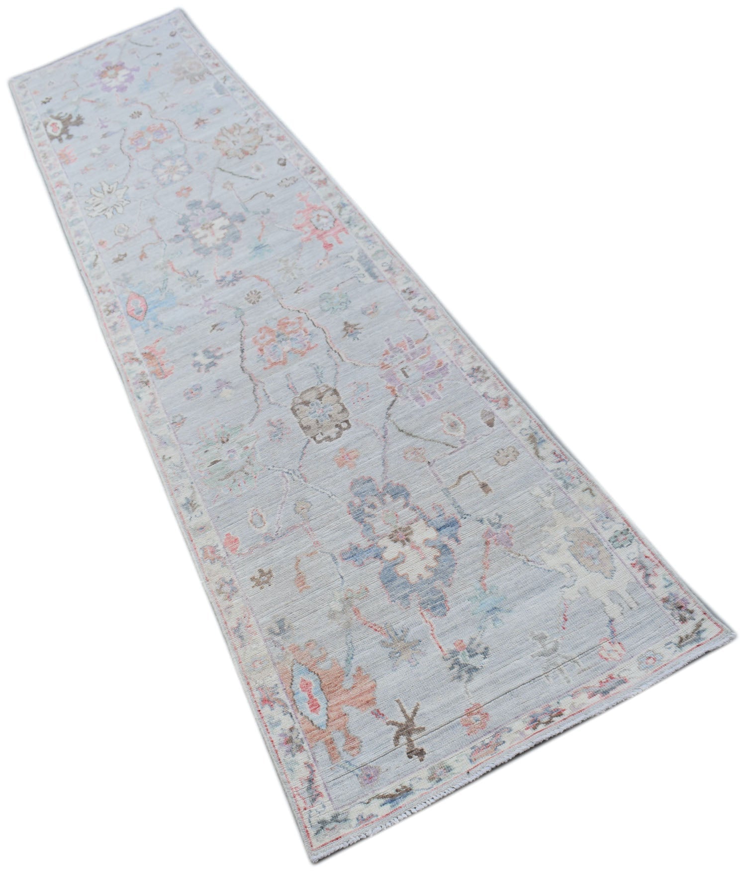 A handmade Afghan Oushak runner rug featuring a traditional floral pattern in soft pastel tones.