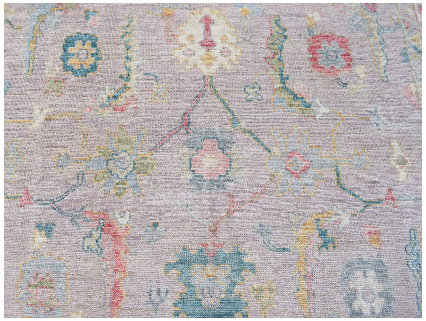 A handmade Afghan Oushak rug featuring a traditional floral pattern in soft pastel tones.