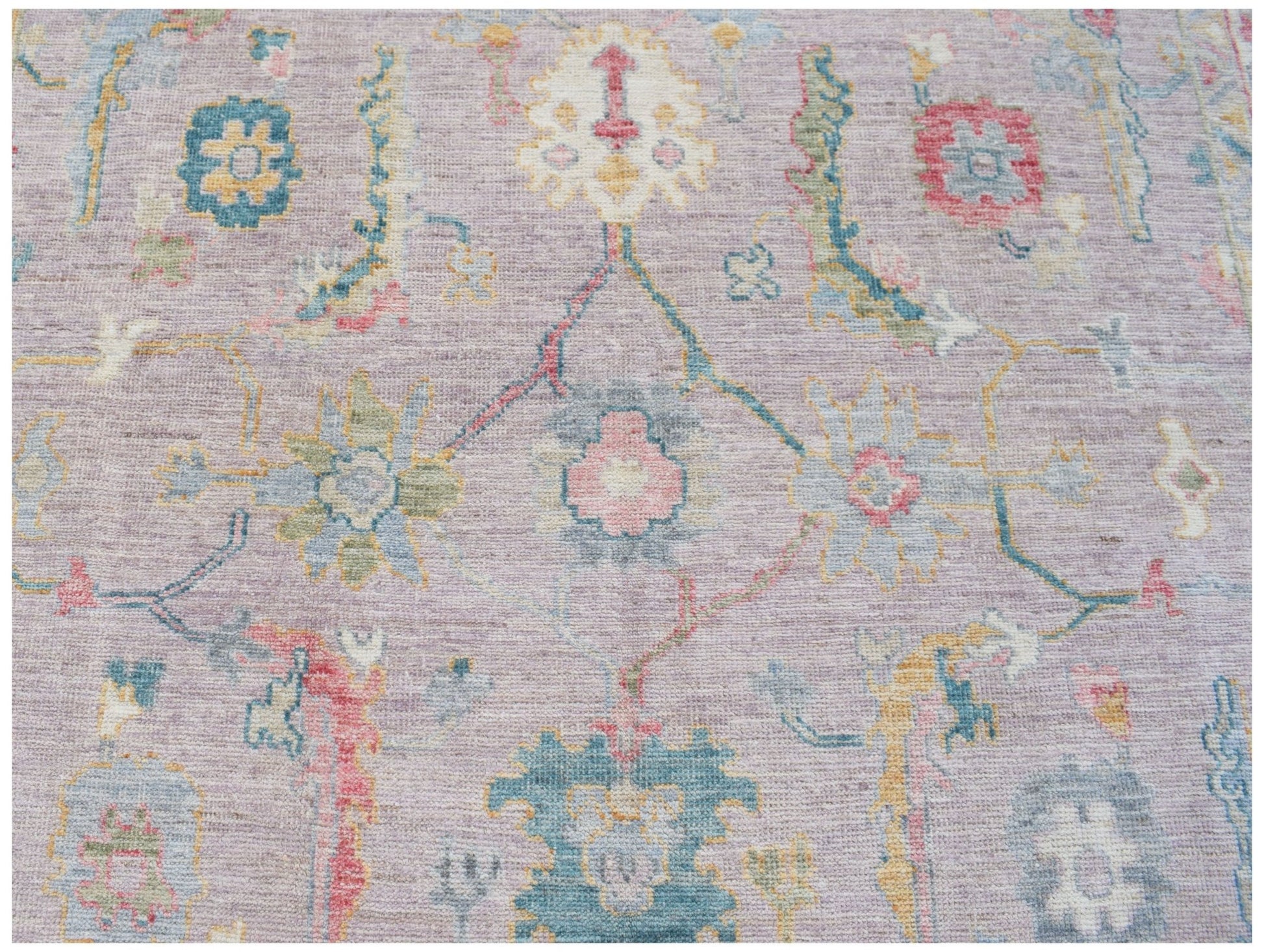 A handmade Afghan Oushak rug featuring a traditional floral pattern in soft pastel tones.