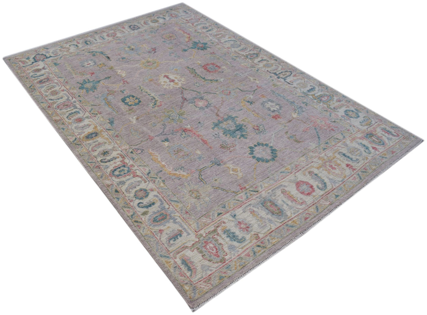 A handmade Afghan Oushak rug featuring a traditional floral pattern in soft, muted tones.
