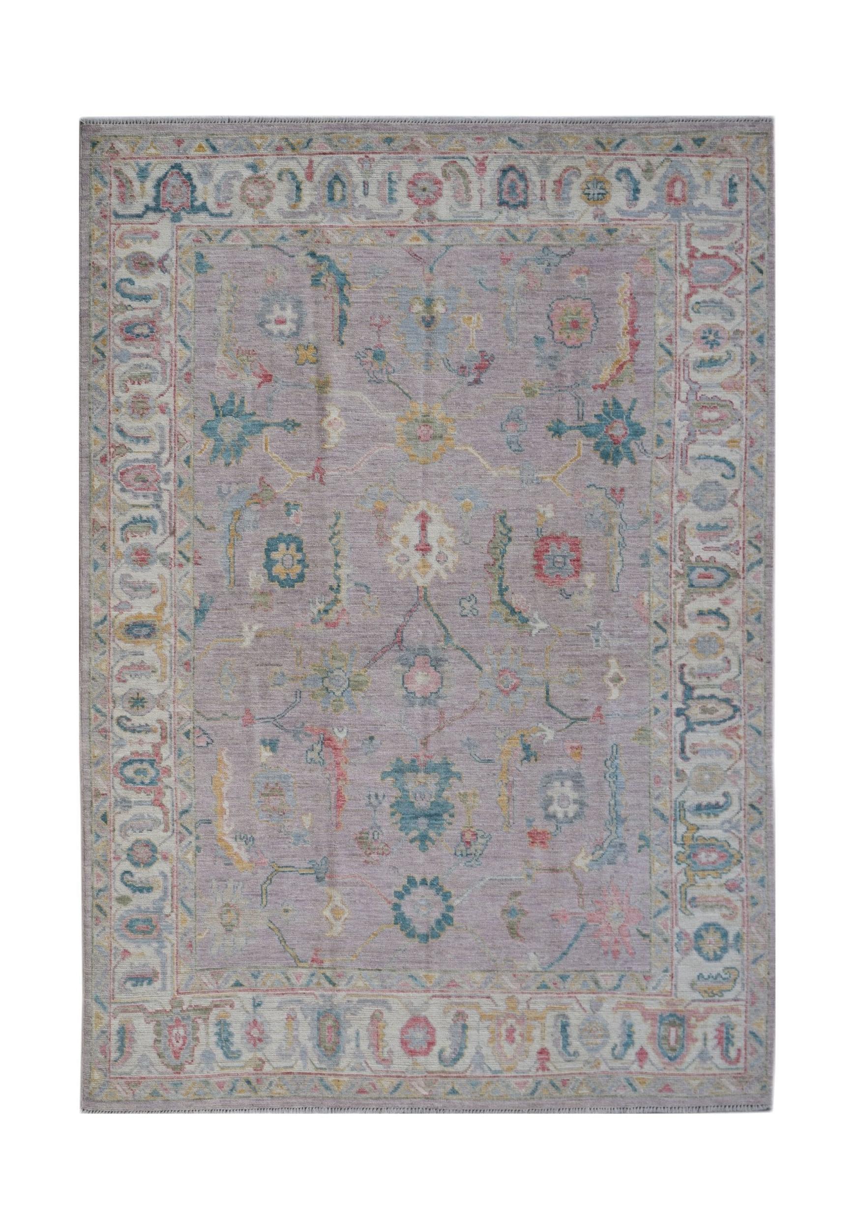 A handmade Afghan Oushak rug featuring a traditional floral pattern in soft lavender and blue tones.