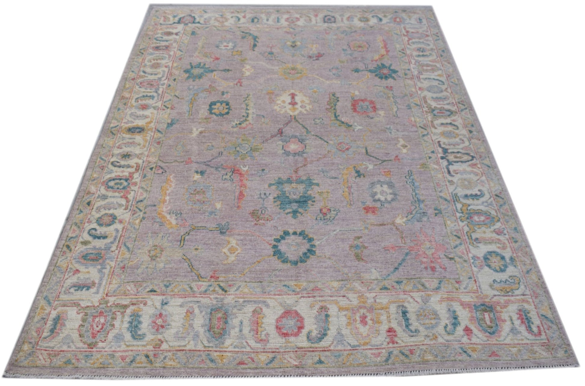 A handmade Afghan Oushak rug featuring a traditional floral pattern in soft pastel tones.