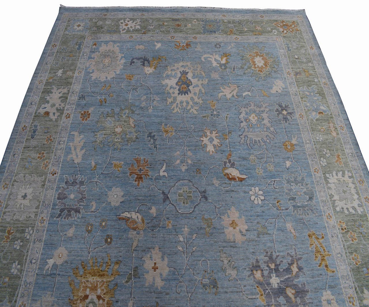 A handmade Afghan Oushak rug featuring a traditional floral pattern in shades of blue and green.