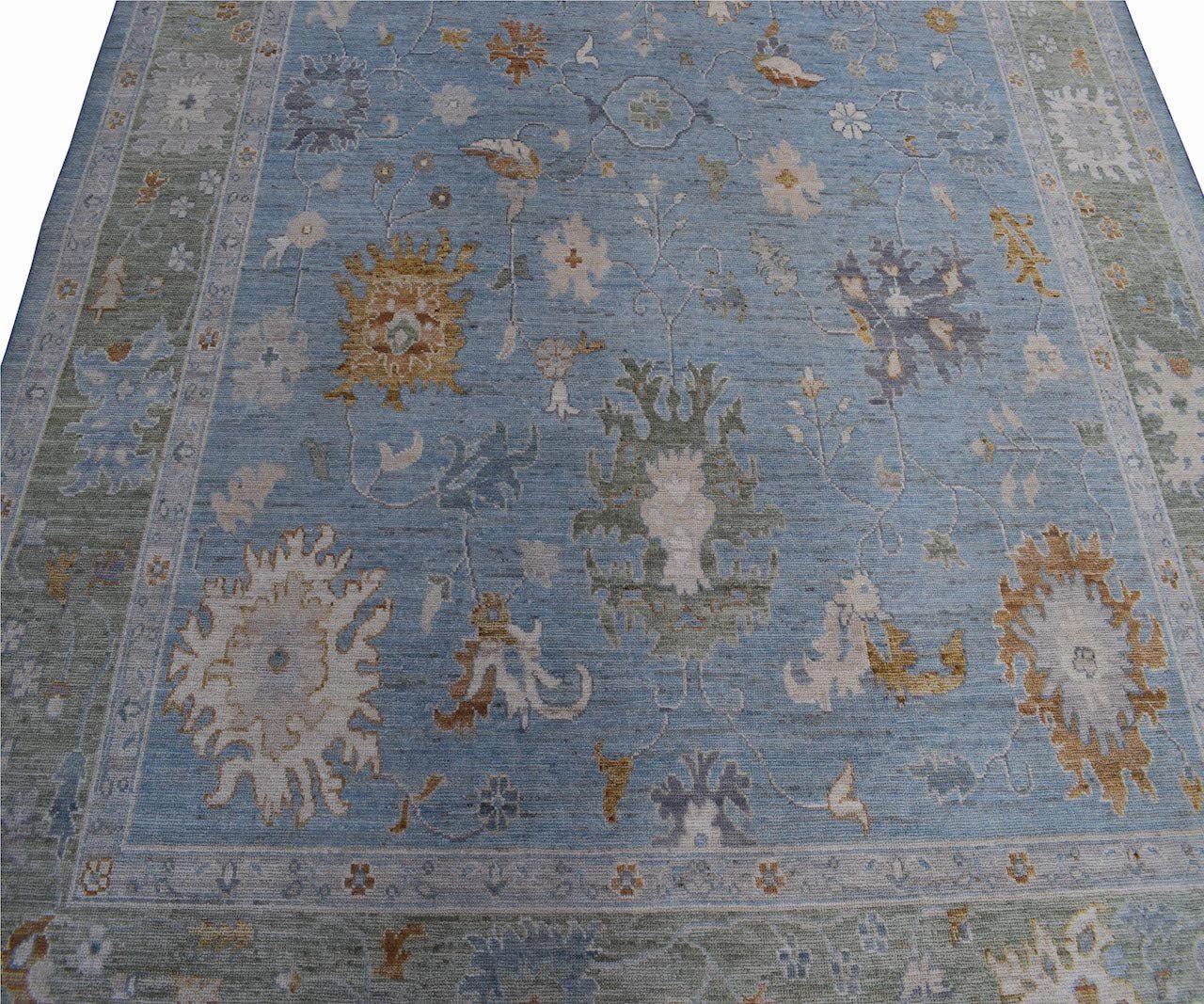 Handmade Afghan Oushak rug featuring a traditional floral pattern in shades of blue and tan.