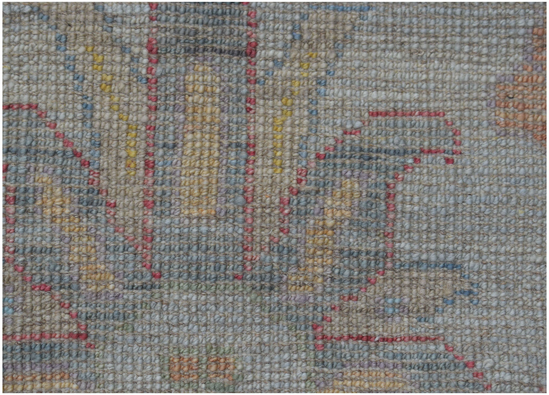 A close-up view of a handmade Afghan Oushak rug featuring a traditional pattern in muted tones.