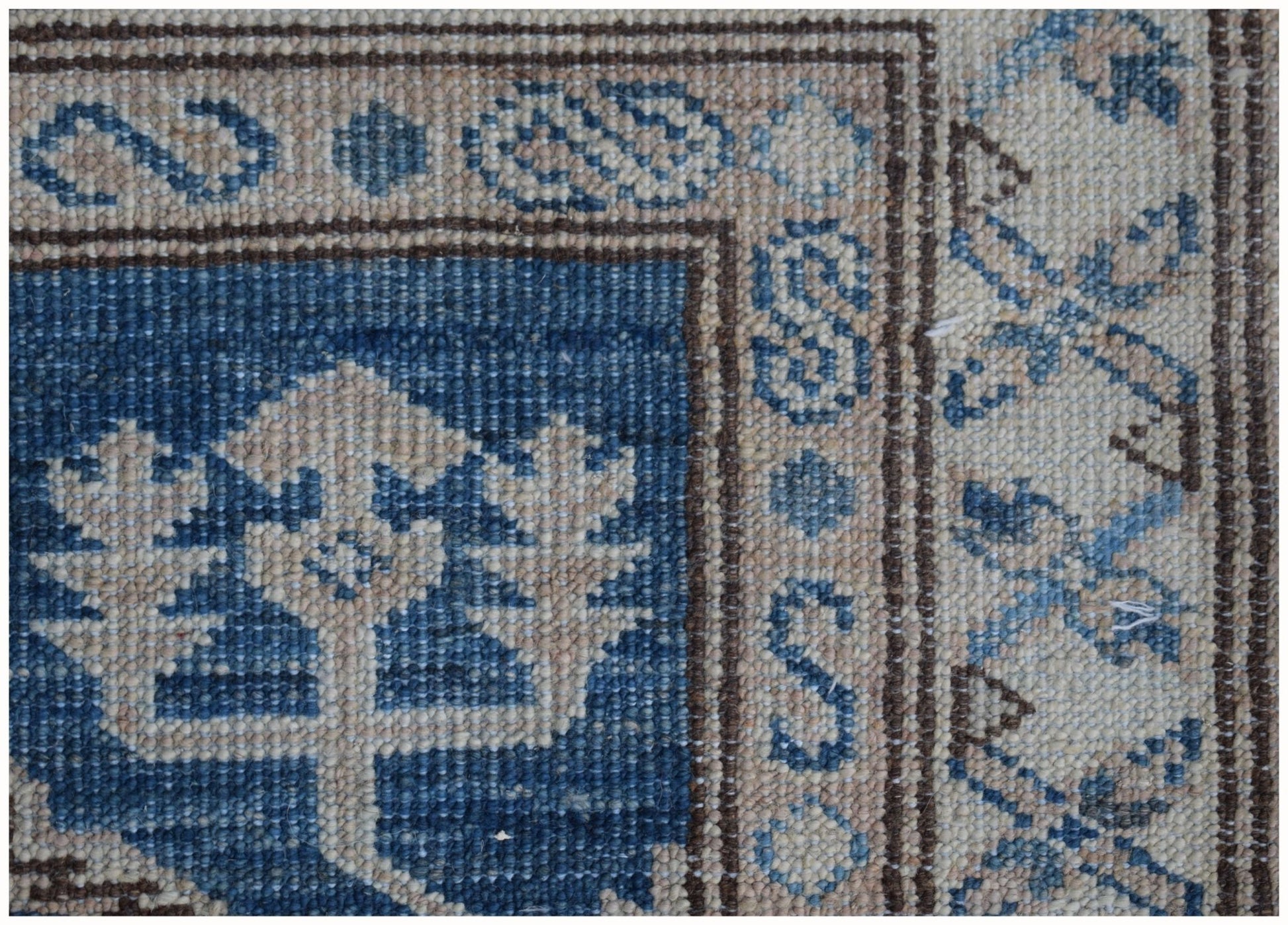 A close-up of an Afghan Super Kazakh runner featuring traditional blue and beige geometric motifs.