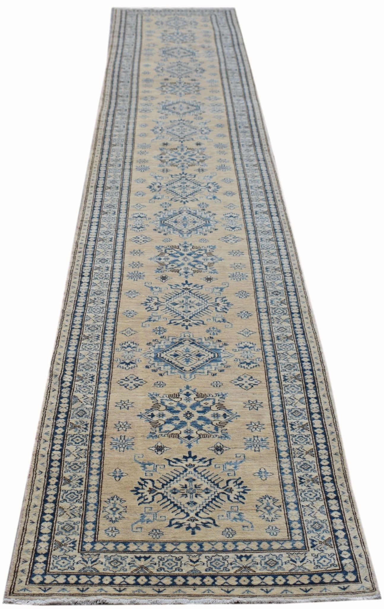 A long, handmade Afghan Super Kazakh runner rug featuring traditional blue geometric motifs on a beige field.