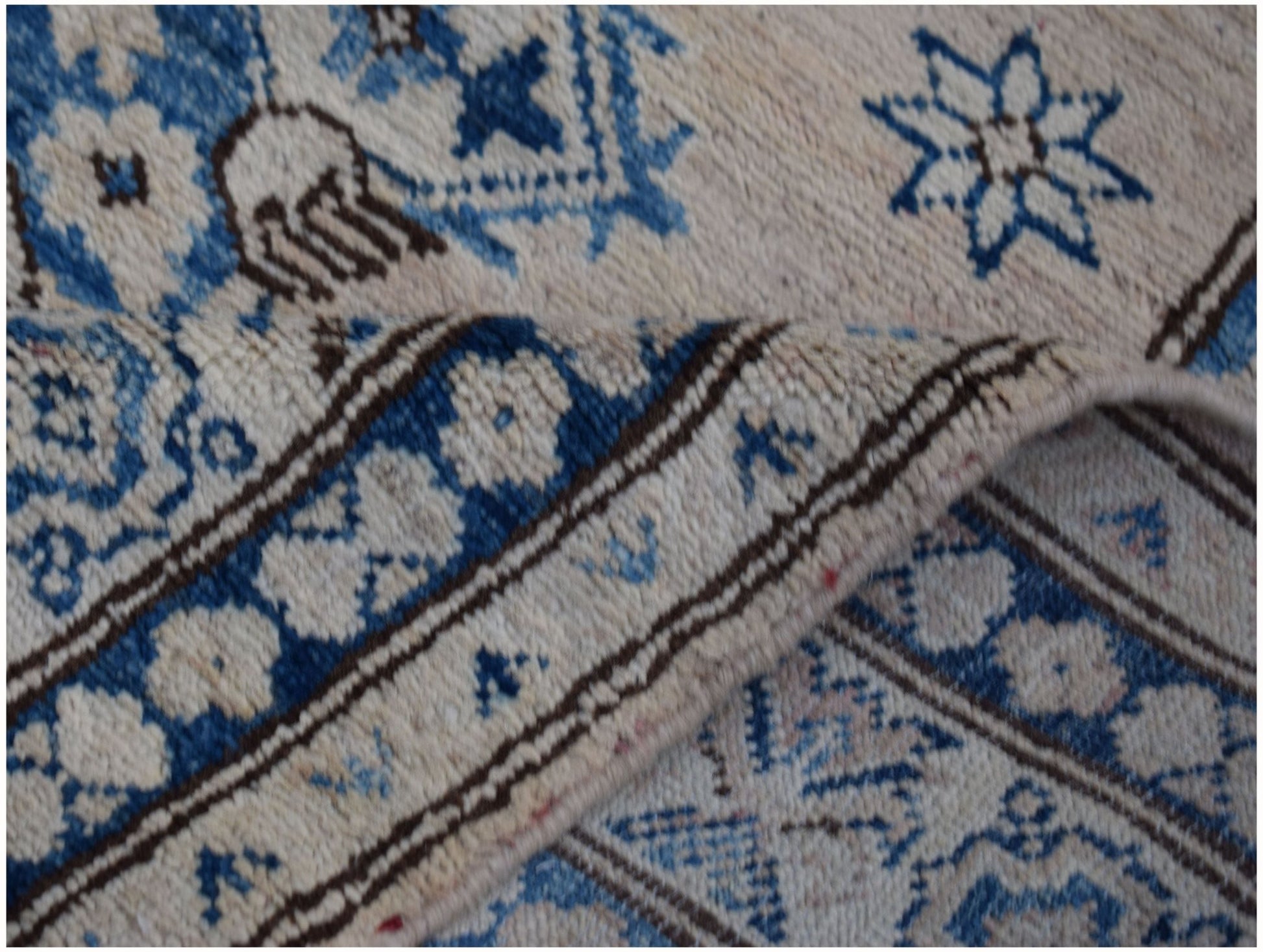 A handmade Afghan Super Kazakh runner featuring traditional blue floral motifs on a cream background.