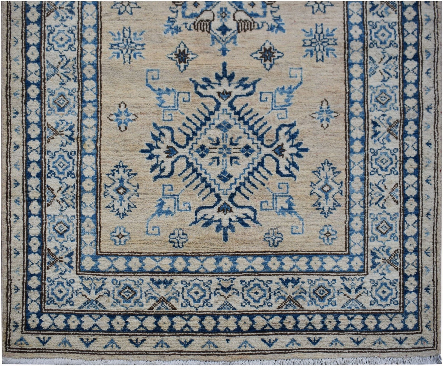 An Afghan Super Kazakh runner rug featuring a blue geometric medallion on a beige wool field.