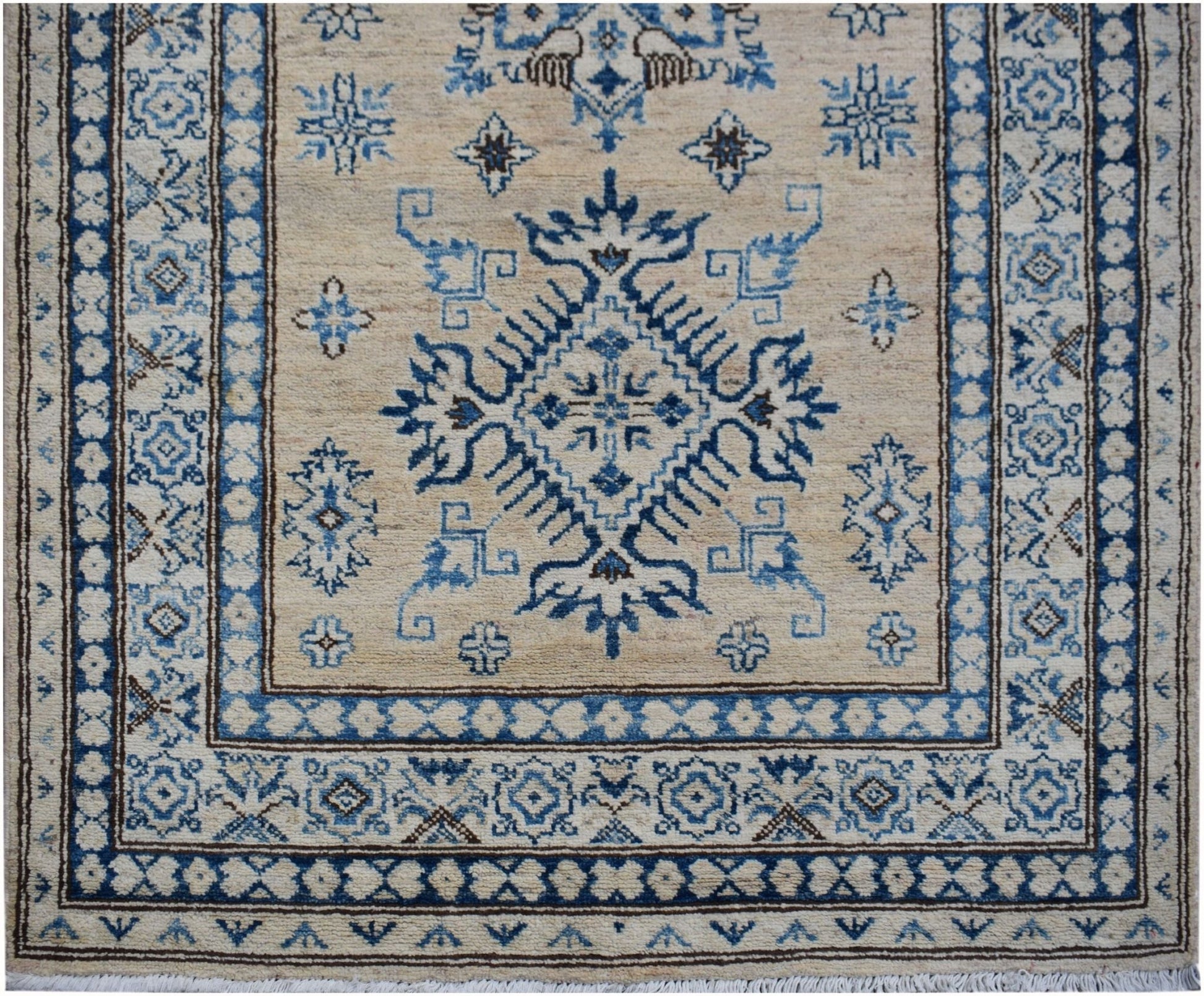 An Afghan Super Kazakh runner rug featuring a blue geometric medallion on a beige wool field.