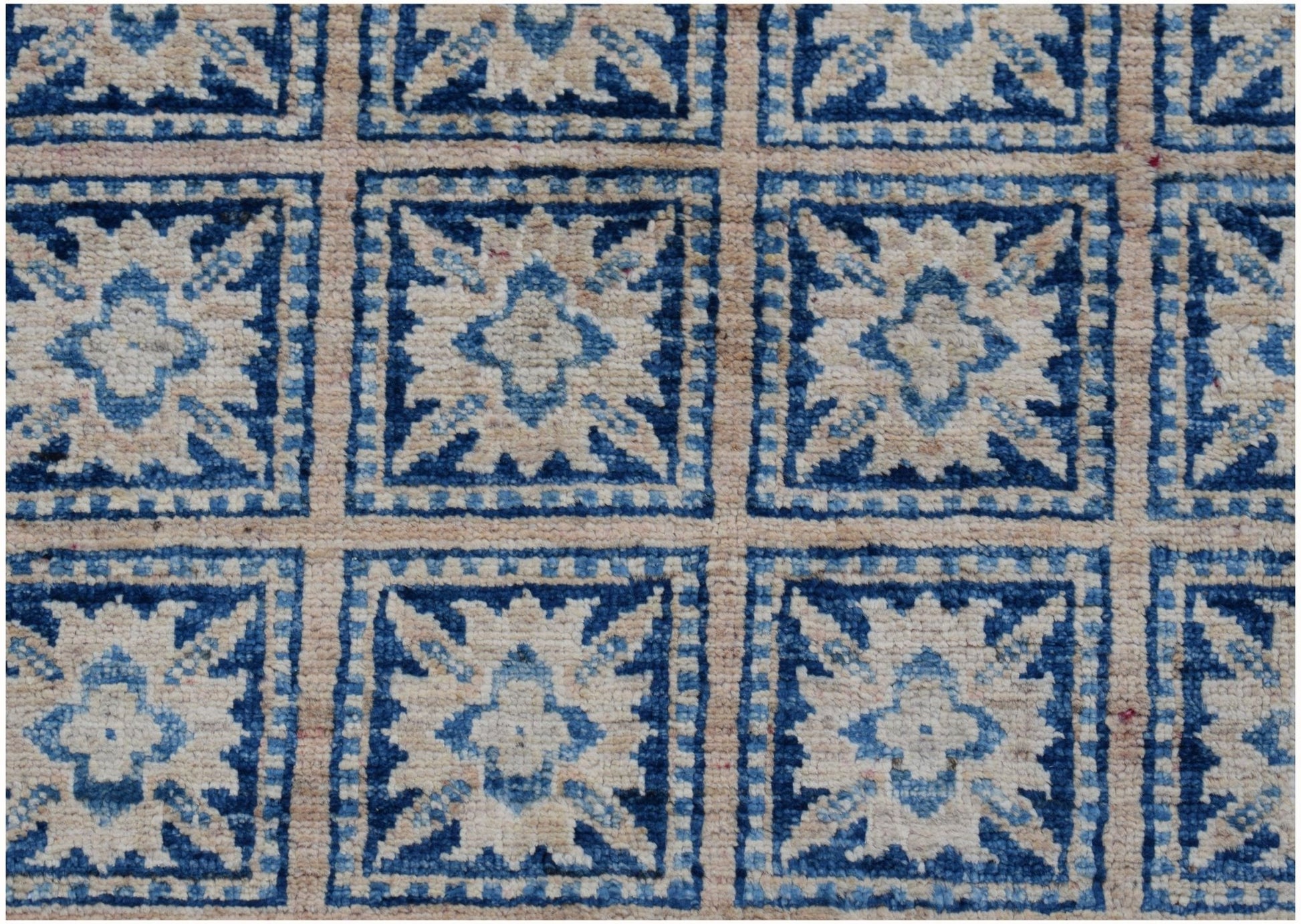 An Afghan Chobi rug featuring a repeating grid of blue and cream geometric floral motifs.