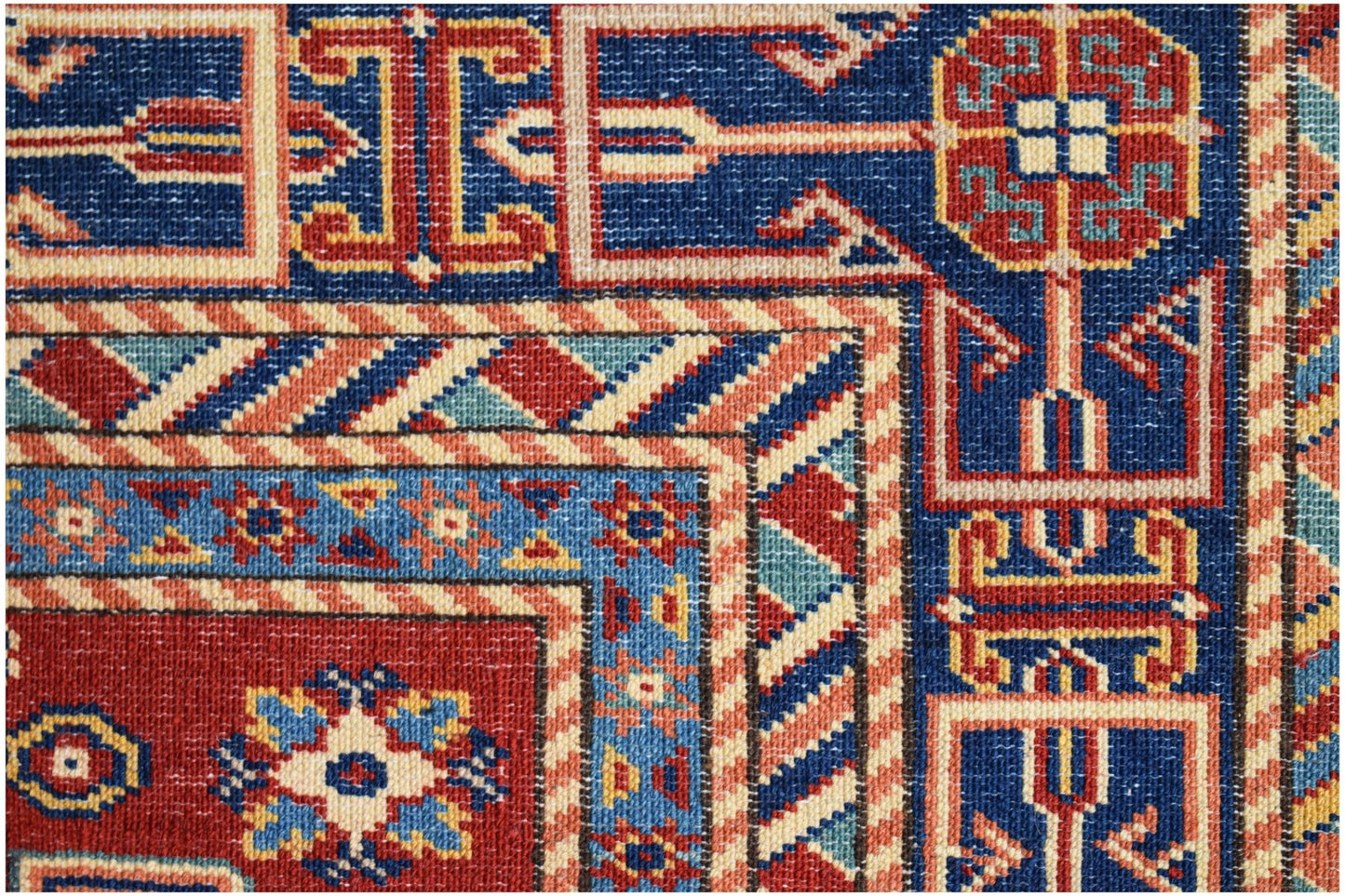 A close-up of an Afghan Super Kazakh rug featuring traditional geometric motifs in red and blue.