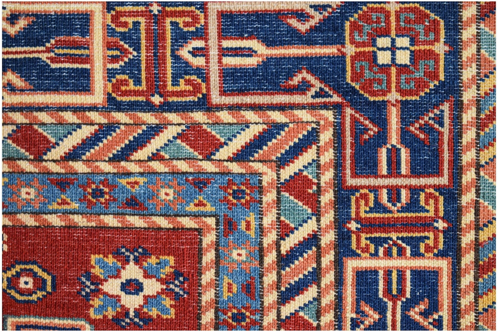 A close-up of an Afghan Super Kazakh rug featuring traditional geometric motifs in red and blue.