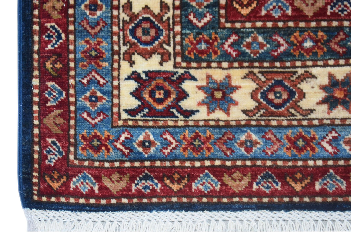 A close-up of an Afghan Super Kazakh rug featuring traditional geometric patterns in red and blue.