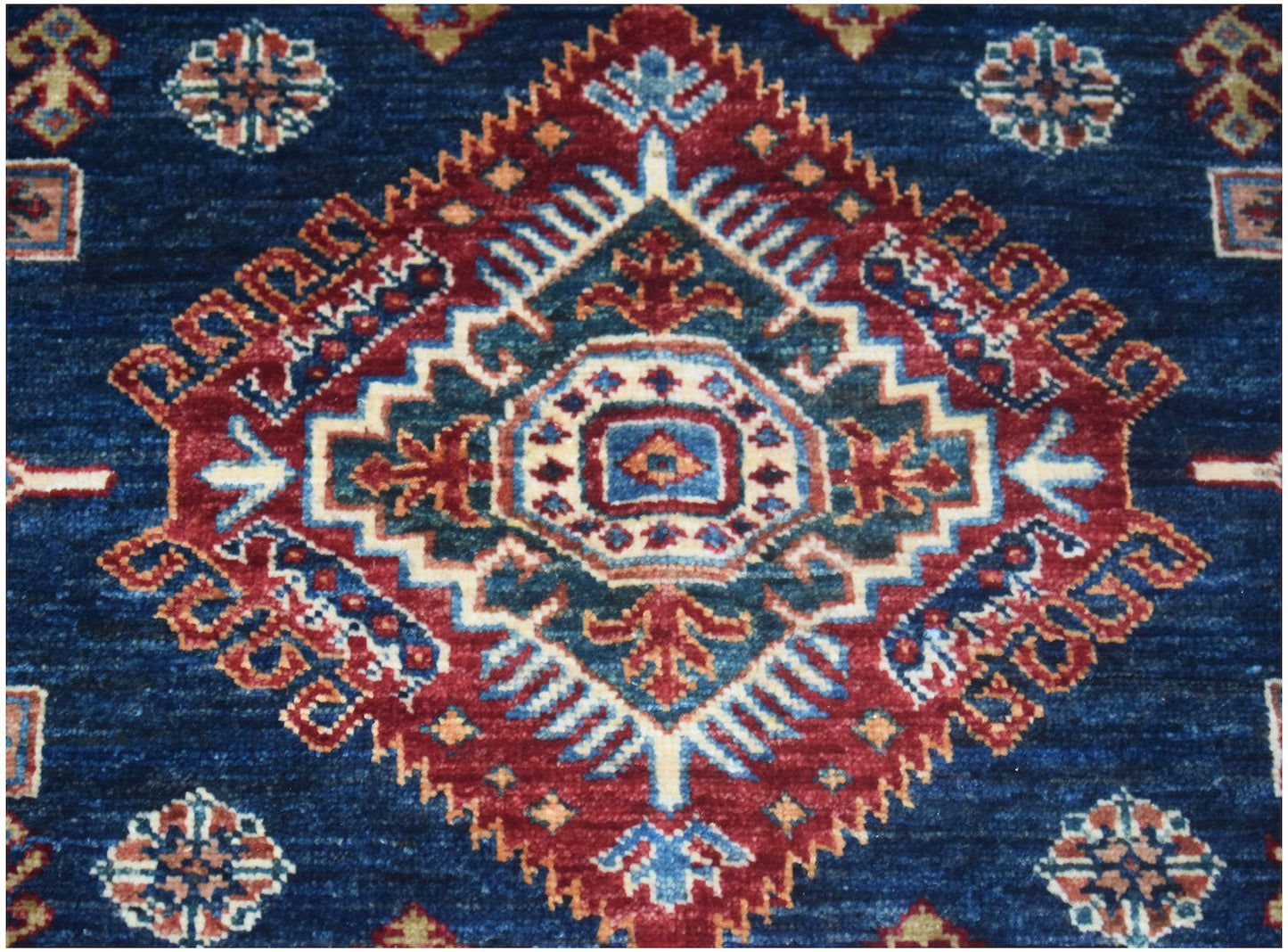 Handmade Afghan Super Kazakh rug featuring a central geometric medallion on a deep blue field.