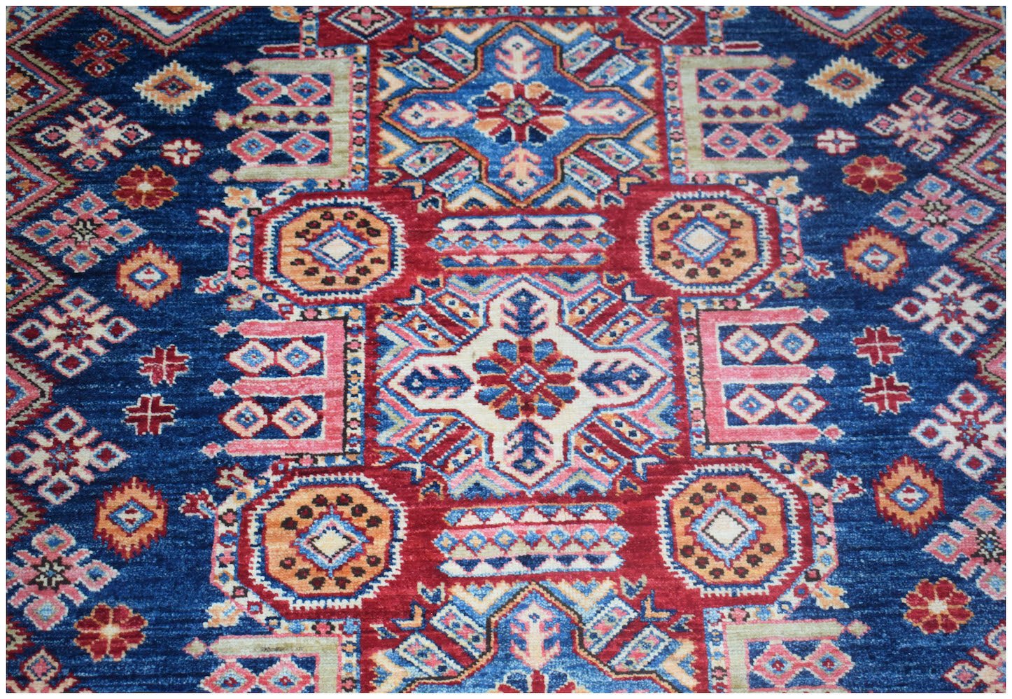 A handmade Afghan Super Kazakh rug featuring traditional geometric motifs in blue, red, and cream.