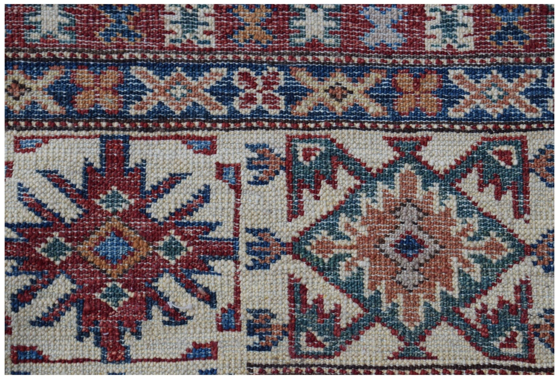 A handmade Afghan Super Kazakh rug featuring traditional geometric motifs in red, blue, and tan.