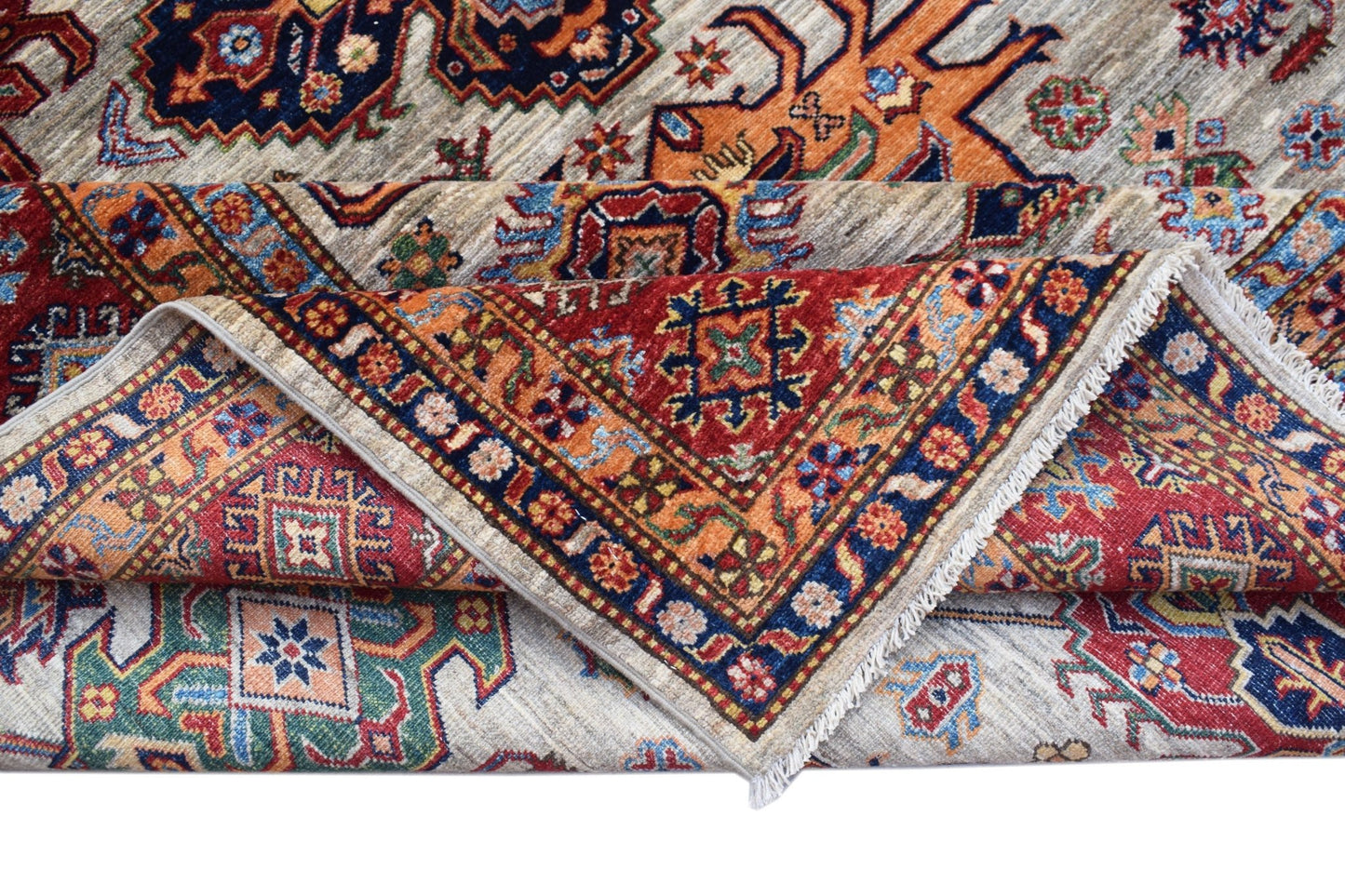 A handmade Afghan Super Kazakh rug featuring traditional geometric motifs in red, blue, and orange.