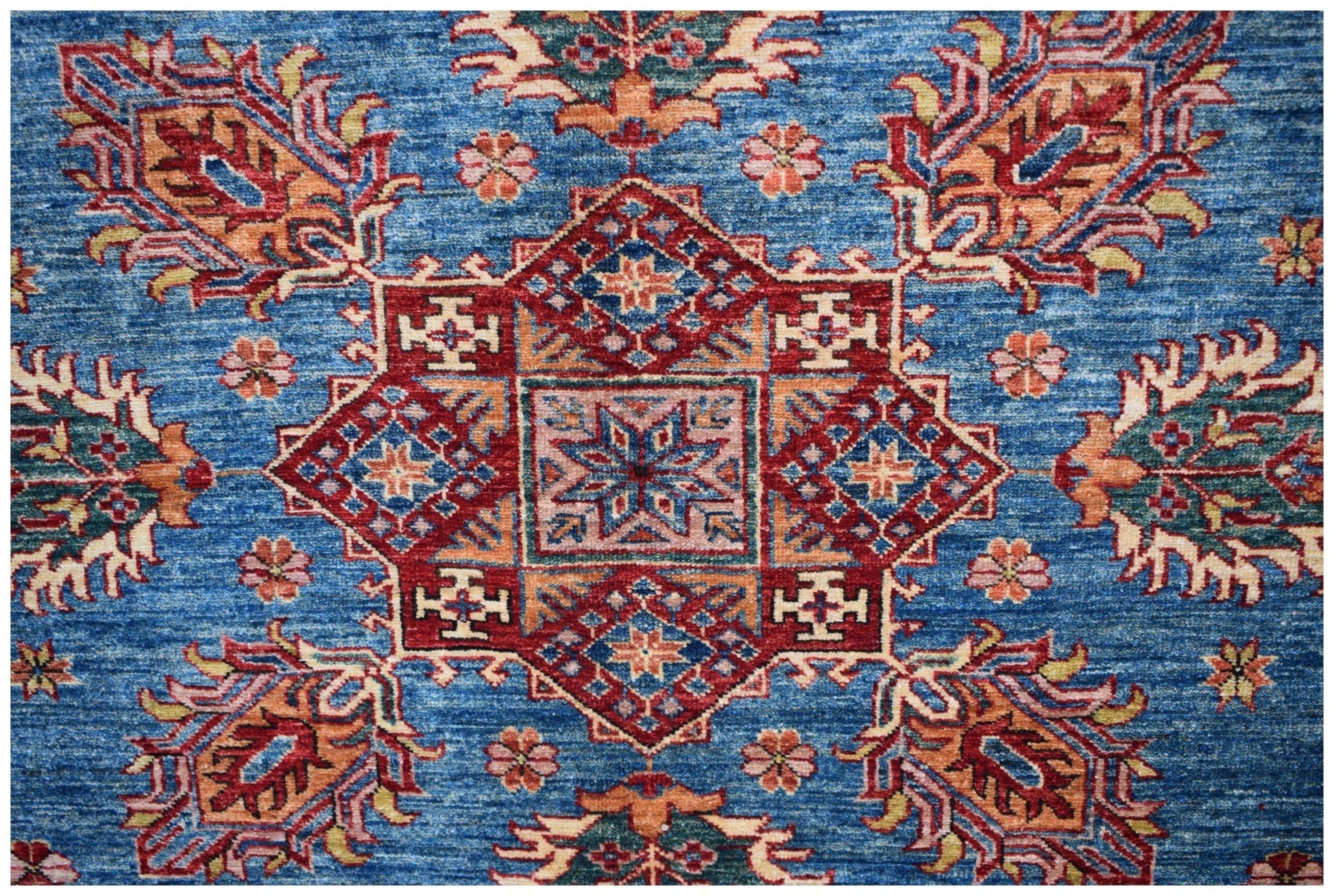 Handmade Afghan Super Kazakh rug featuring a central geometric medallion on a blue field.