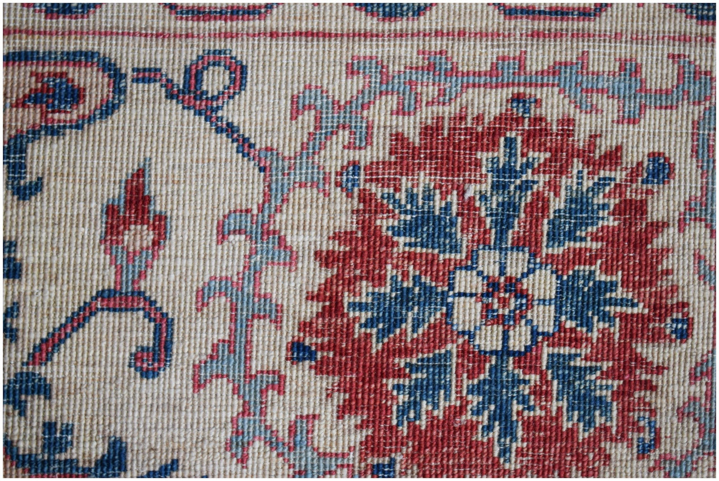 A close-up of an Afghan Chobi rug featuring a red floral medallion on a cream background.