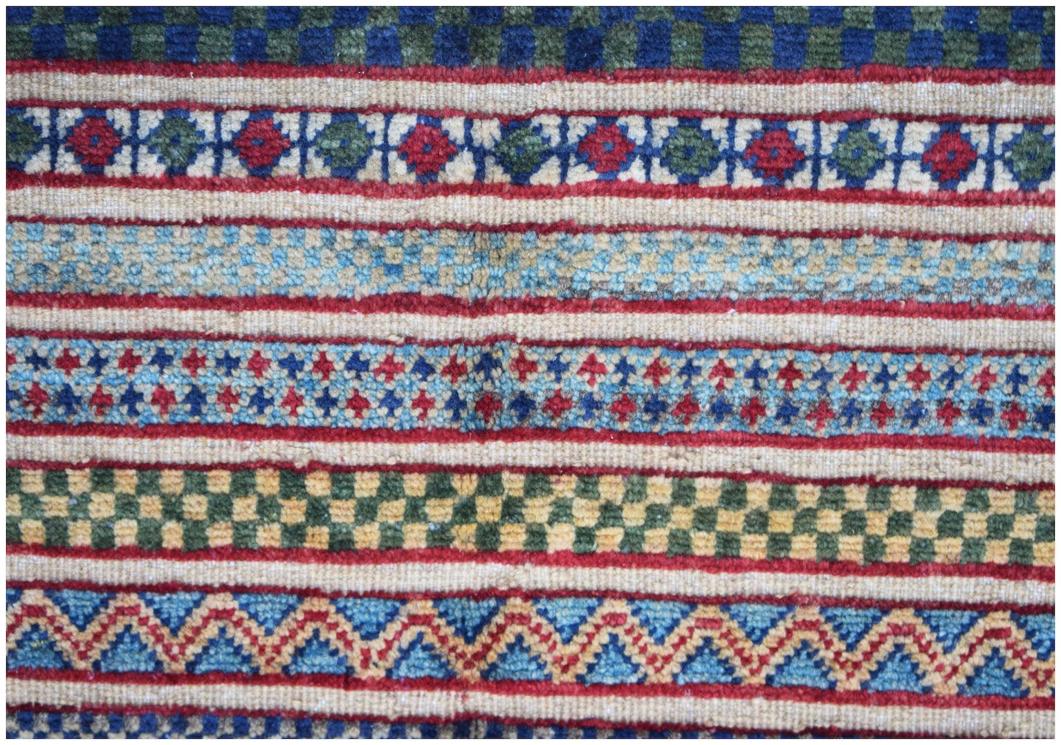 A handmade Afghan runner featuring horizontal bands of geometric patterns in vibrant colors.