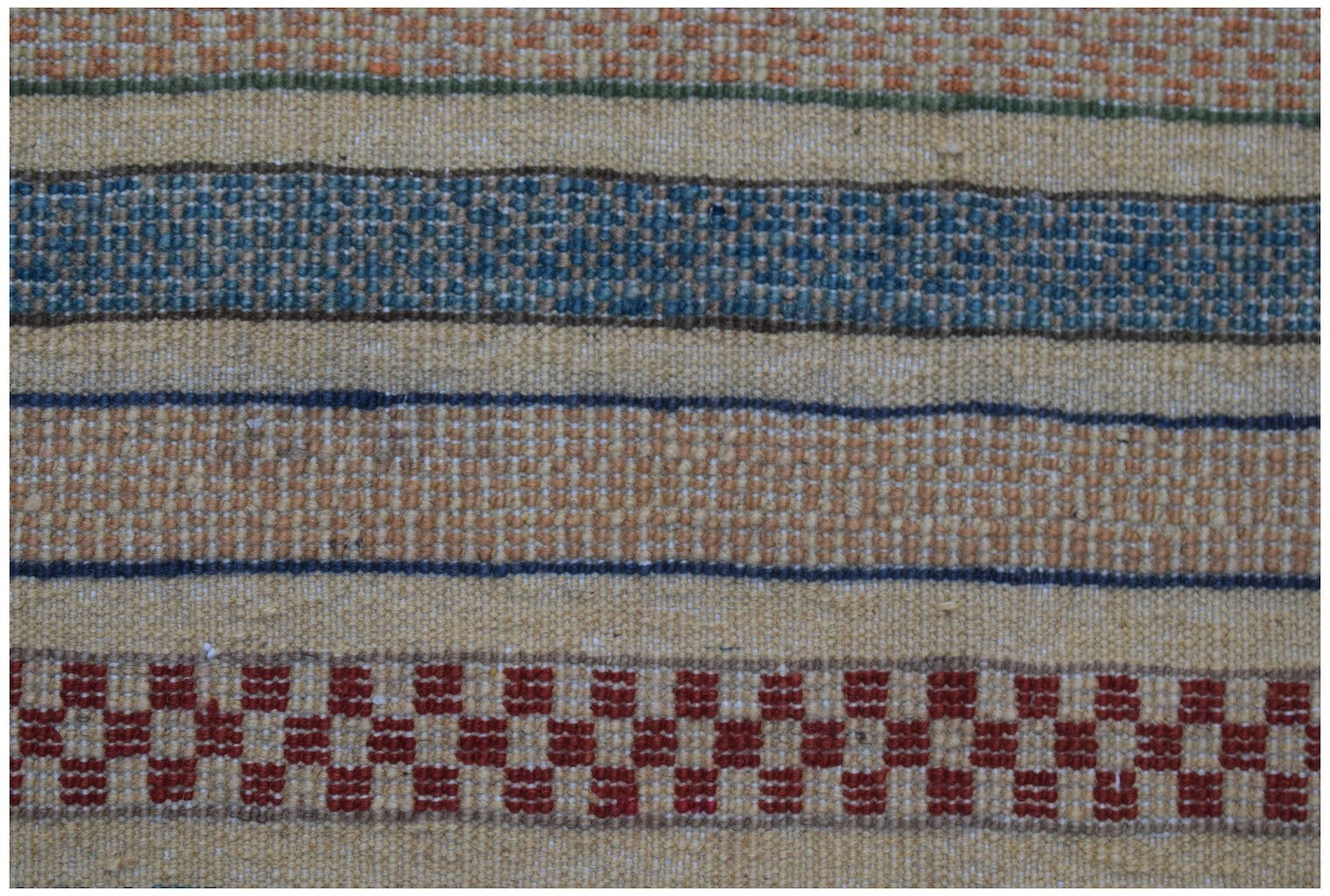 A handmade Afghan runner featuring horizontal stripes in red, blue, and tan wool.