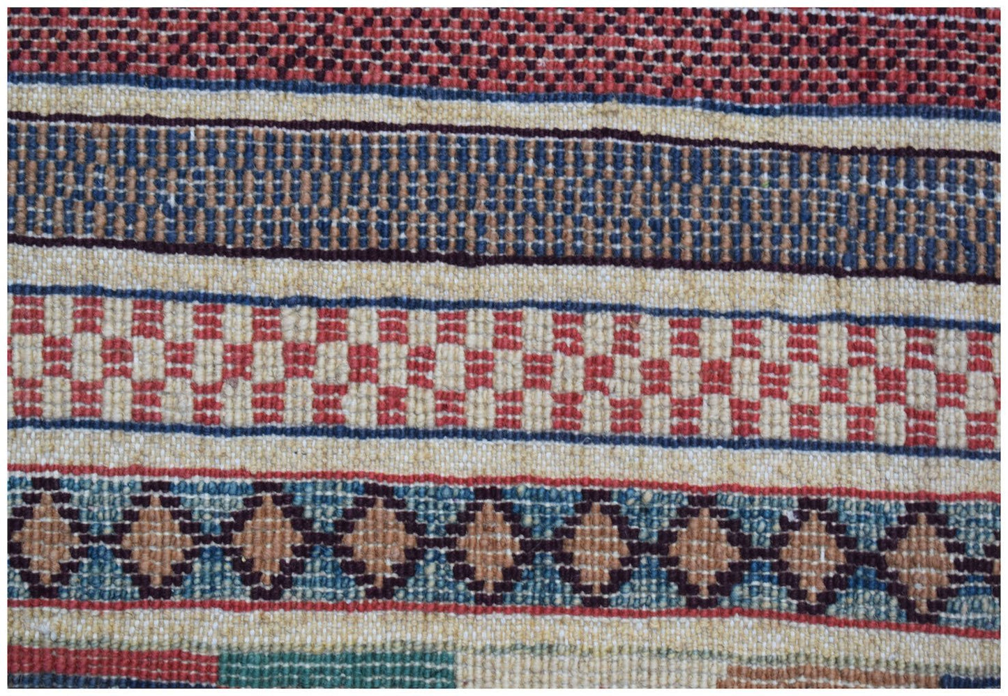 A handmade Afghan runner featuring horizontal bands of geometric patterns in red, blue, and tan.