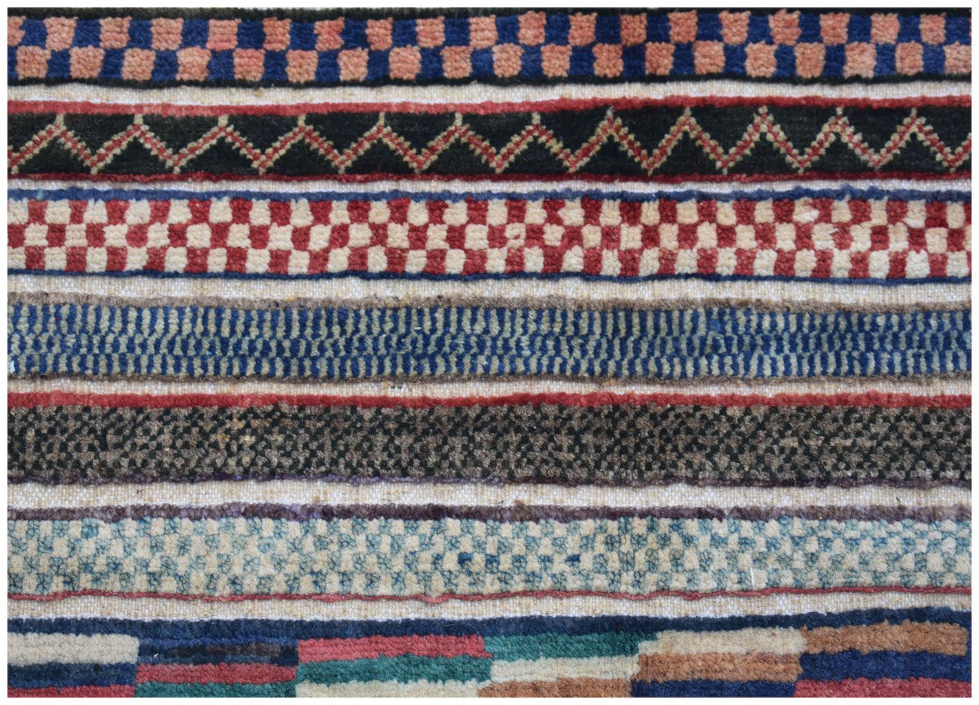 A handmade Afghan runner featuring horizontal bands of geometric patterns in varied colors.