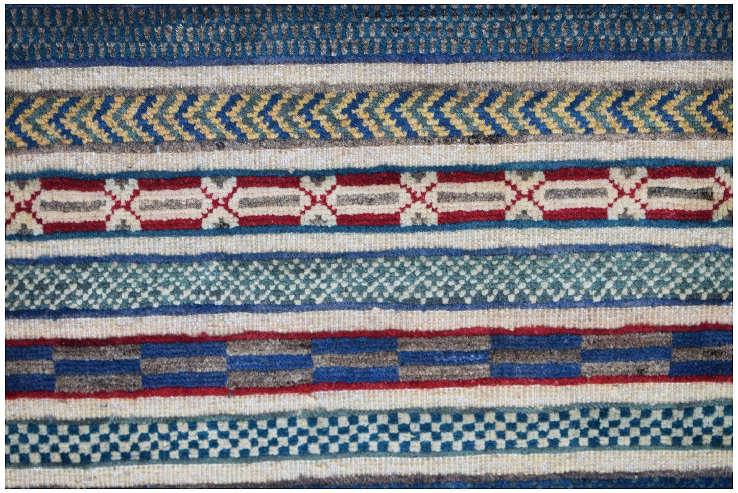 A close-up of an Afghan Yekta rug featuring horizontal bands of geometric patterns in wool.
