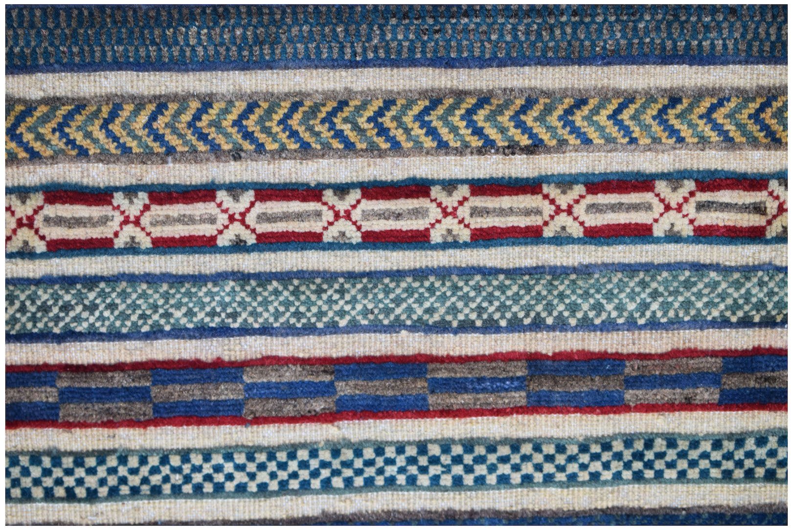 A close-up of an Afghan Yekta rug featuring horizontal bands of geometric patterns in wool.