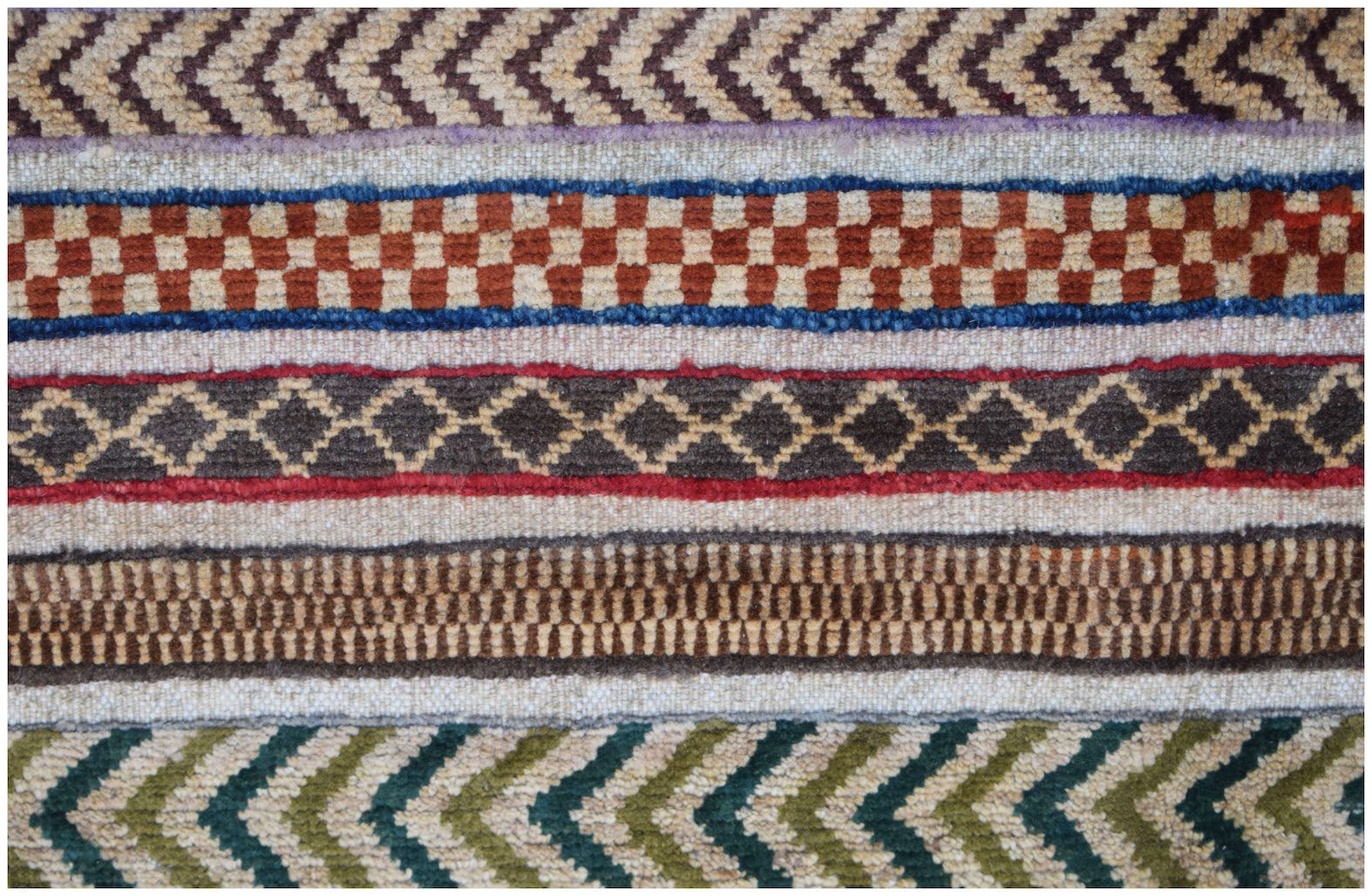 A close-up of an Afghan Yekta rug featuring horizontal bands of geometric patterns and textures.