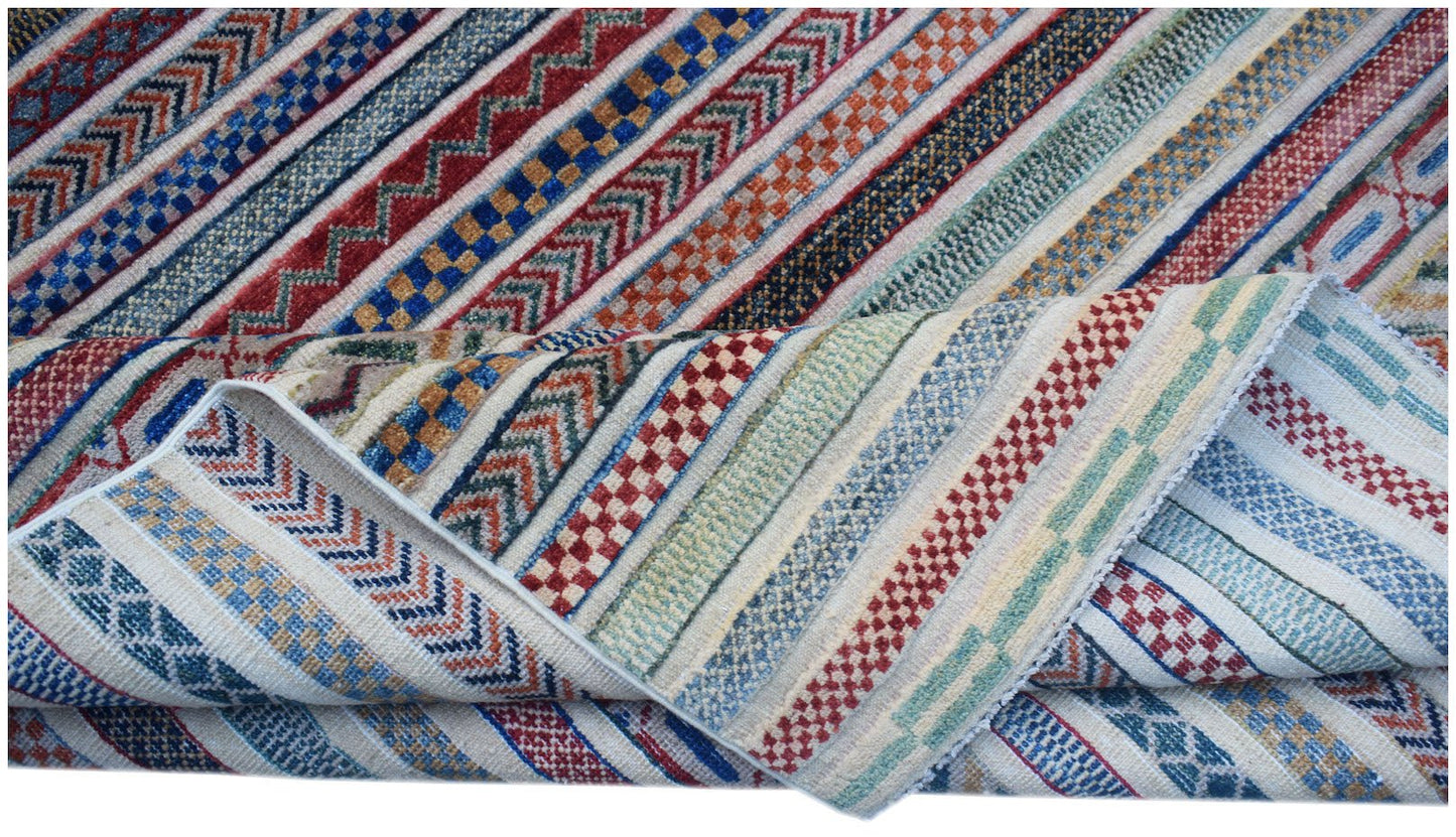 An Afghan Yekta rug featuring a folded corner and a vibrant, multi-colored striped geometric pattern.