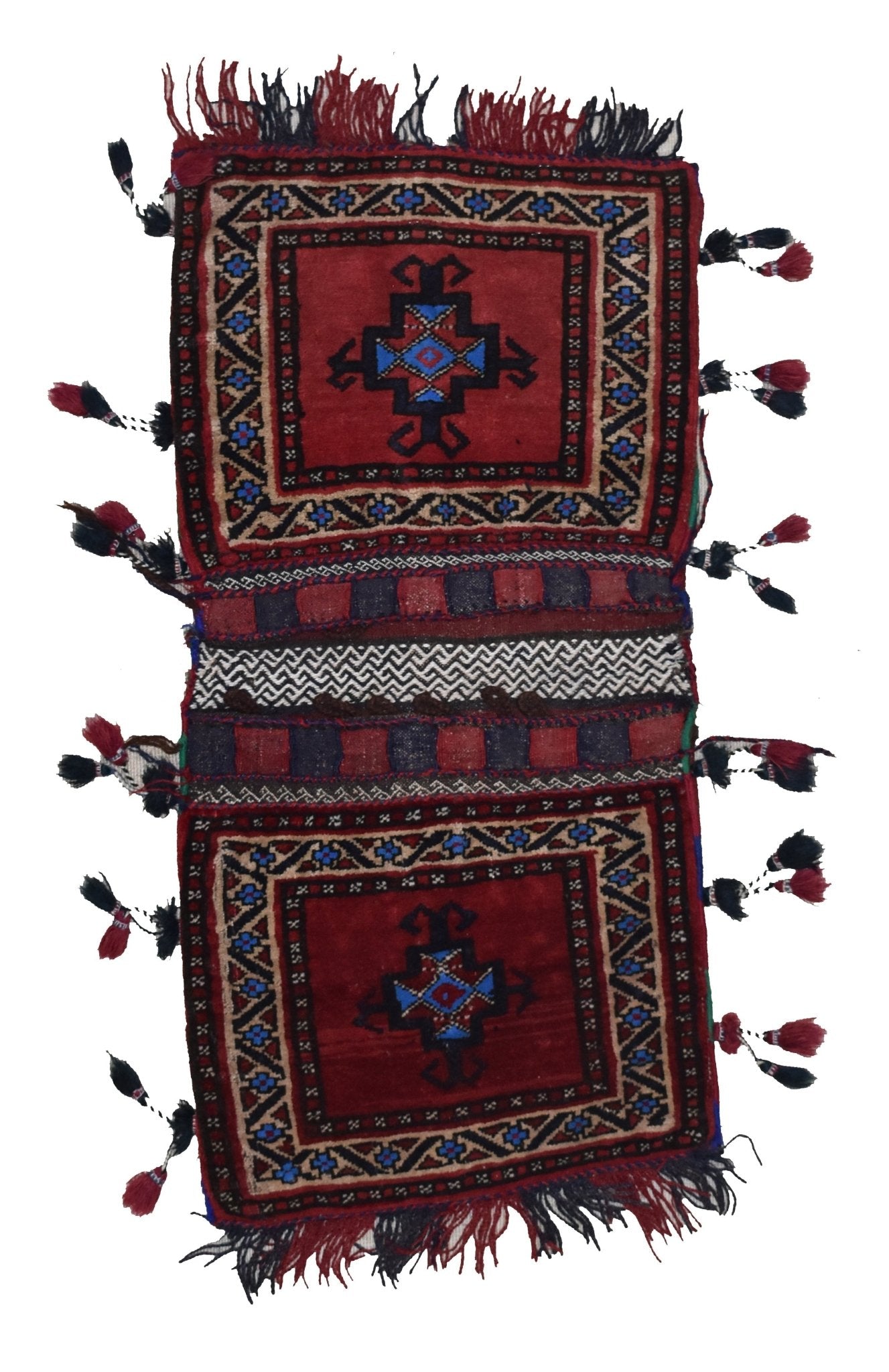 A vintage handmade Afghan wool saddle bag featuring two red panels with geometric motifs and tassels.