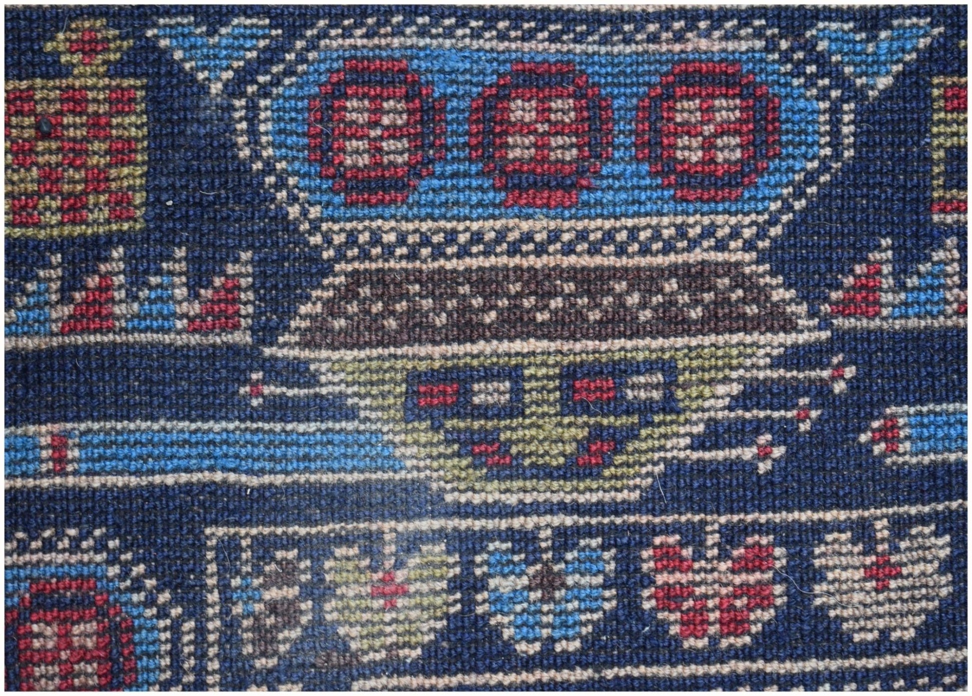 A close-up of a handmade Afghan wool rug featuring intricate geometric and floral motifs.