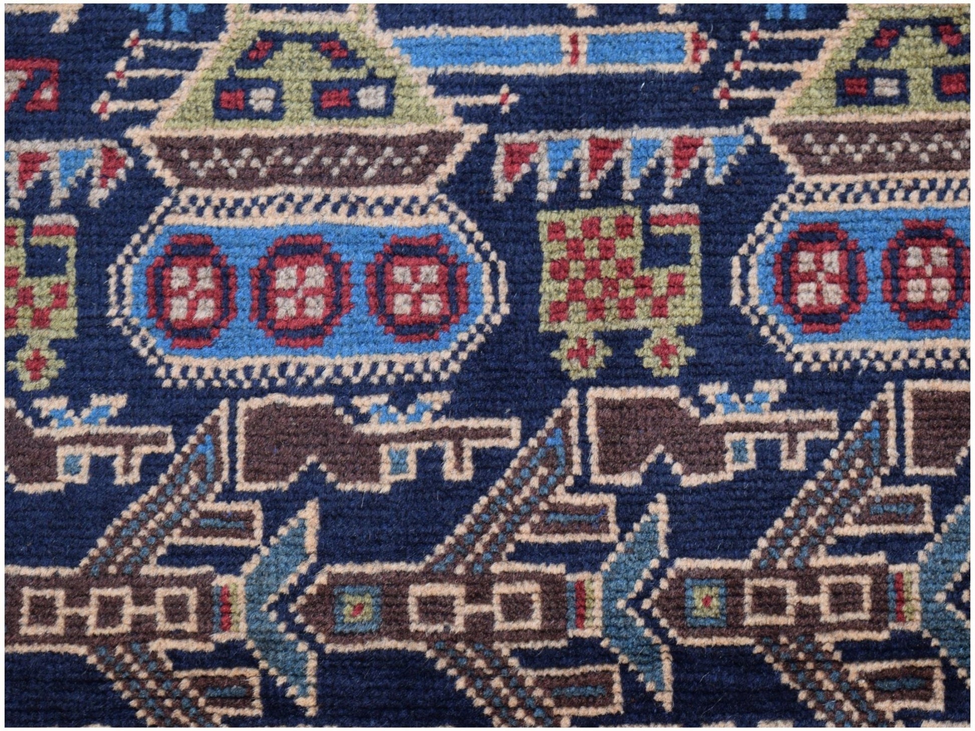 A handmade Afghan wool rug featuring a dark blue background with woven military tank motifs.