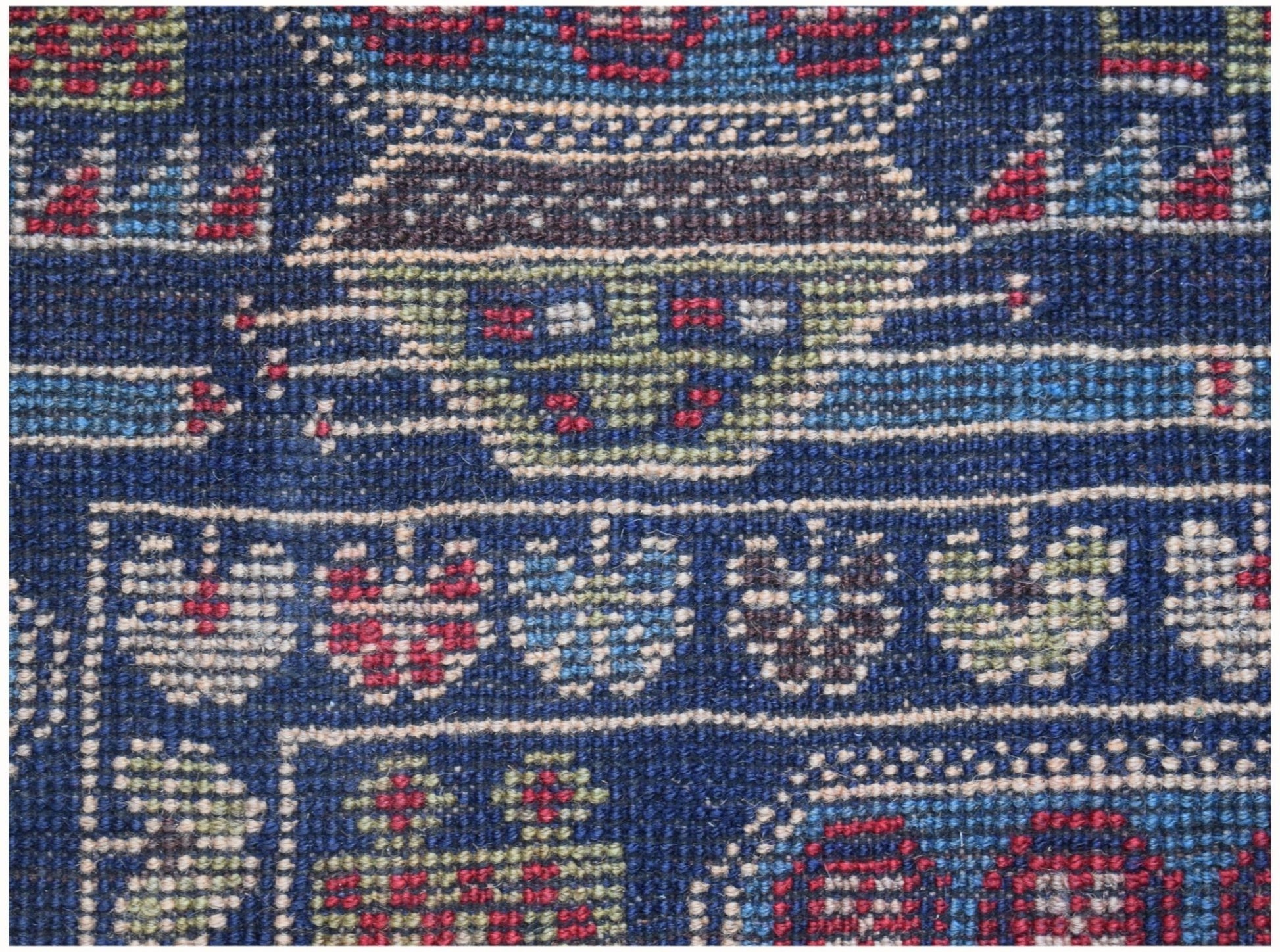 A close-up of a handmade Afghan wool rug featuring intricate geometric and floral patterns.