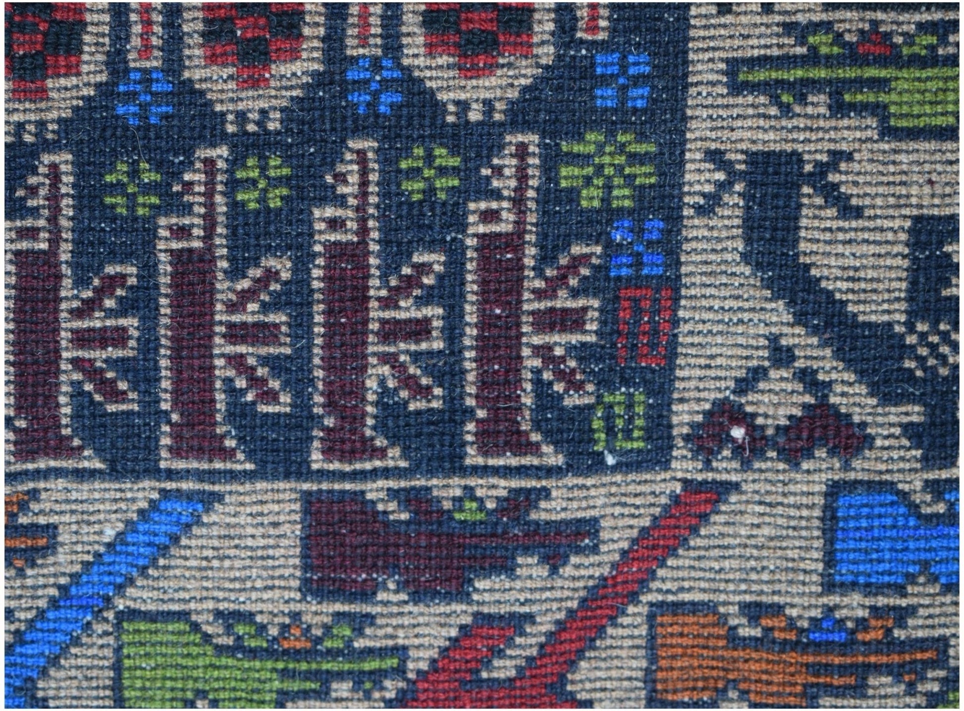 A close-up of a handmade Afghan wool rug featuring geometric patterns and military-themed motifs.