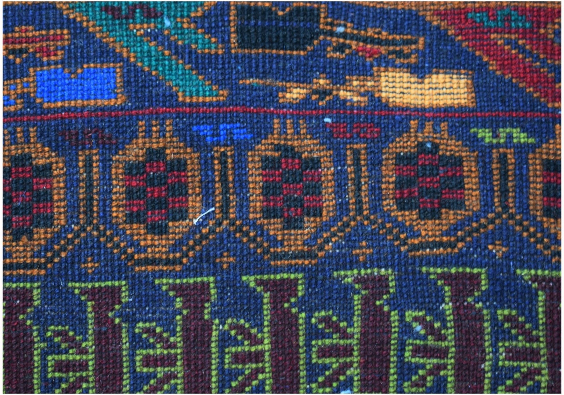 A close-up of a handmade Afghan wool rug featuring geometric patterns and traditional motifs.