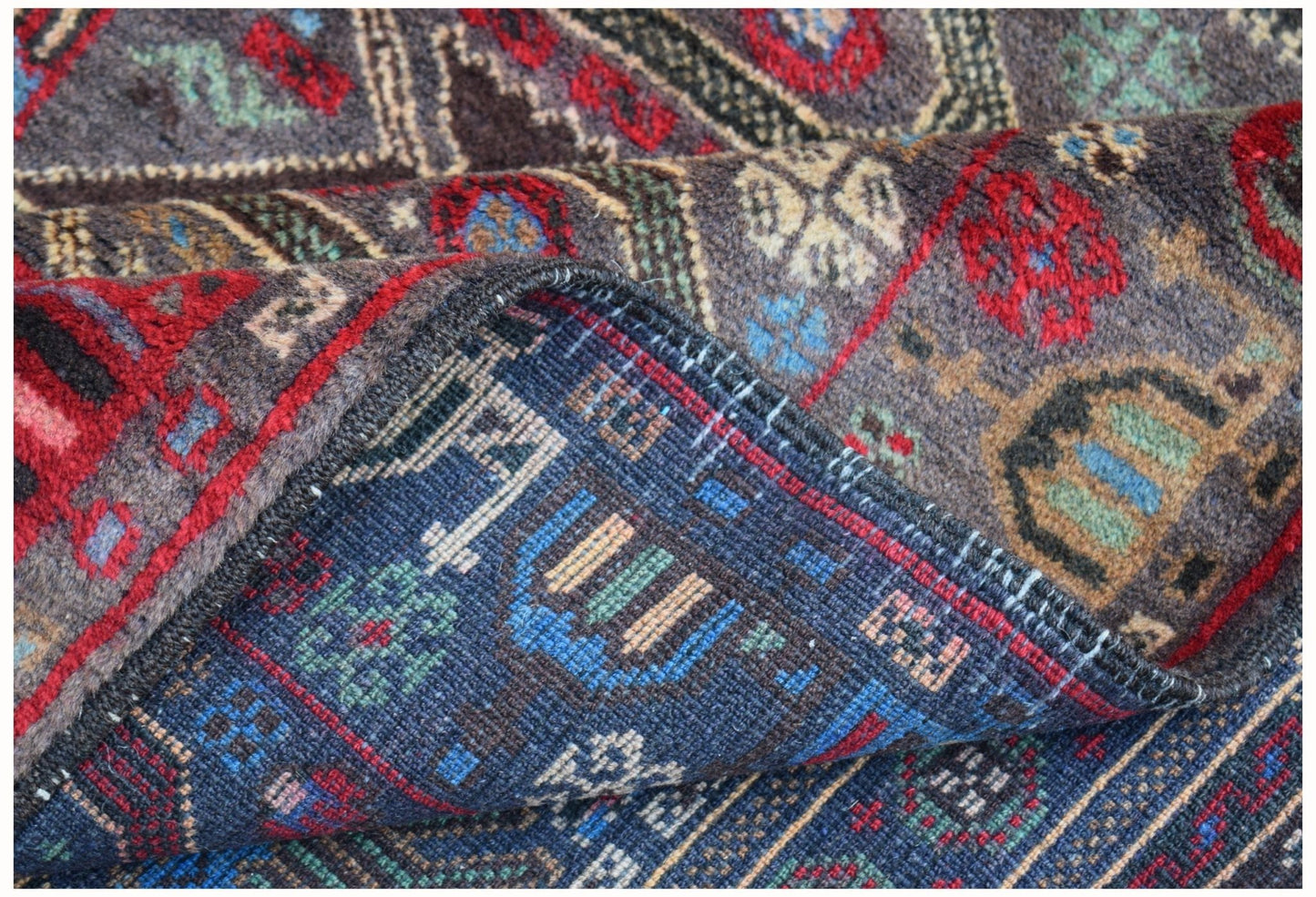A handmade Afghan wool rug featuring intricate geometric patterns in red, blue, and brown tones.