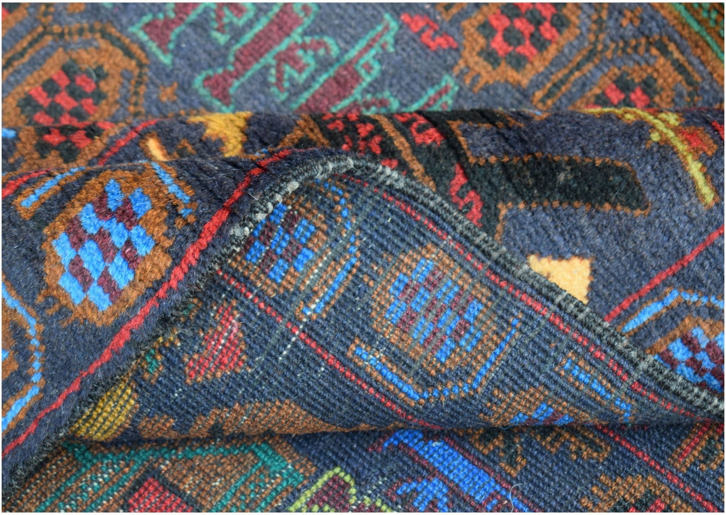 A handmade Afghan wool rug featuring a dark blue background with geometric and patterned motifs.