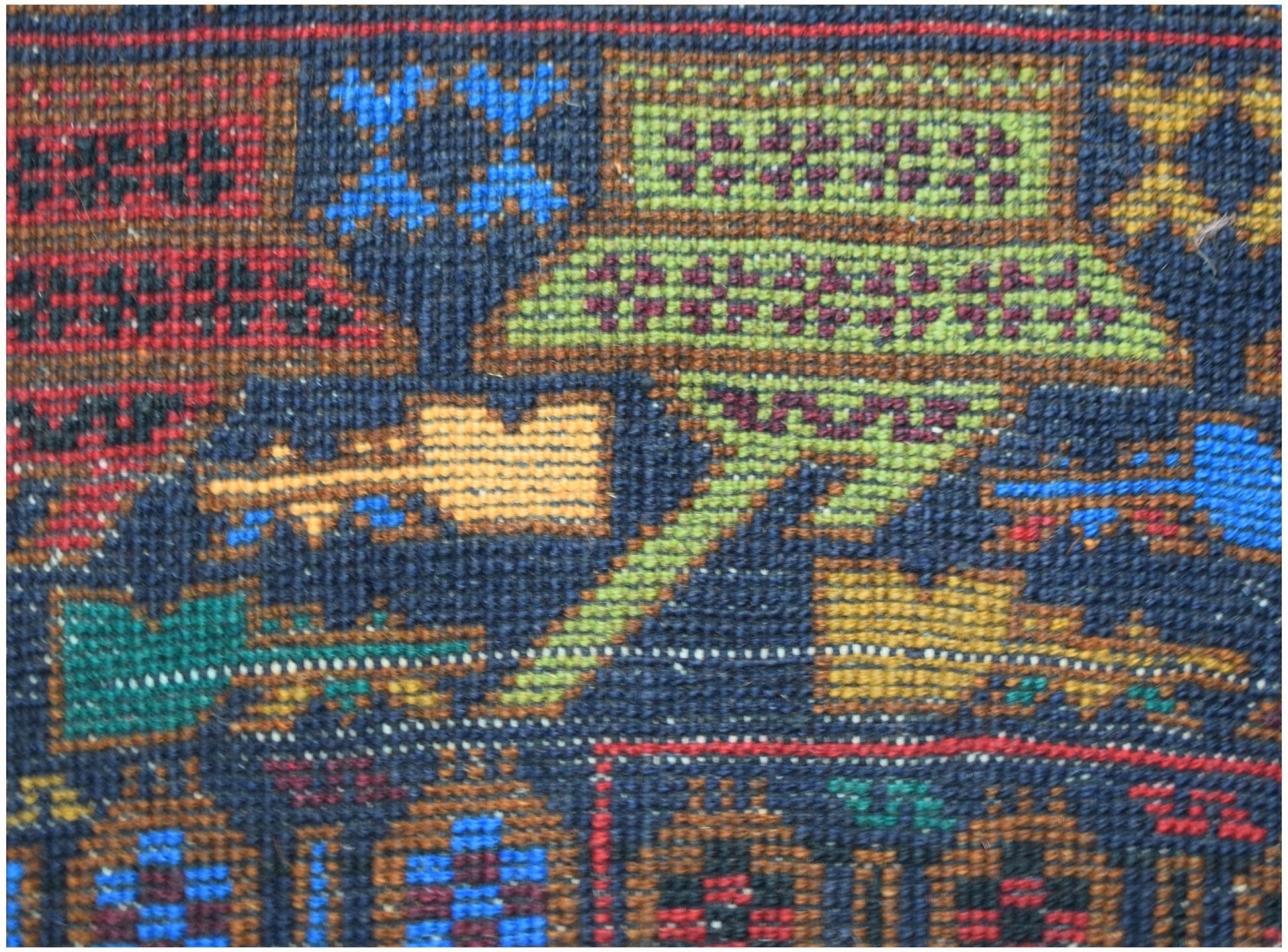 A close-up of a handmade Afghan wool rug featuring intricate geometric and symbolic patterns.