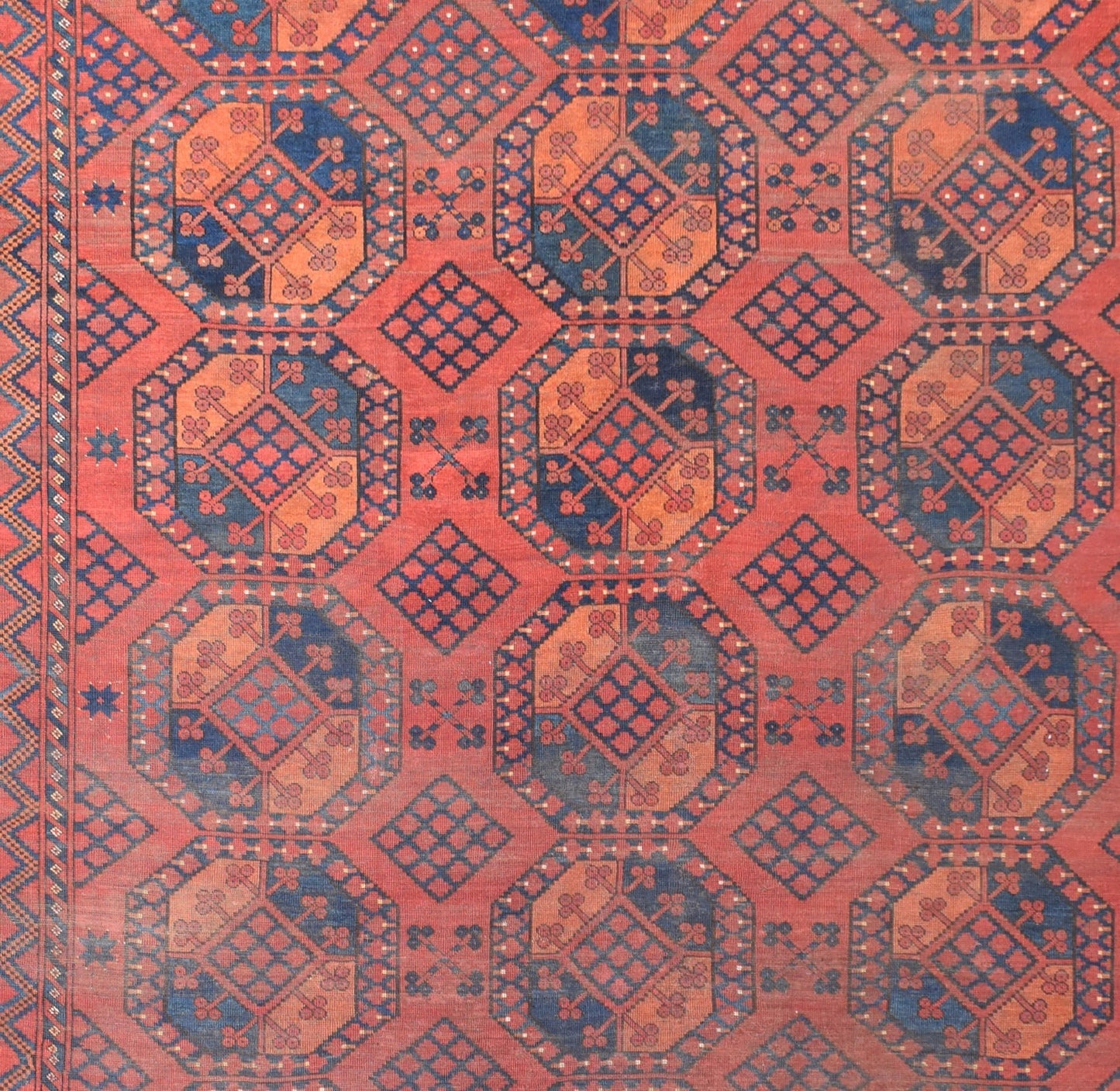 An antique Afghan Turkmen rug featuring a repeating geometric elephant foot motif in red and blue.
