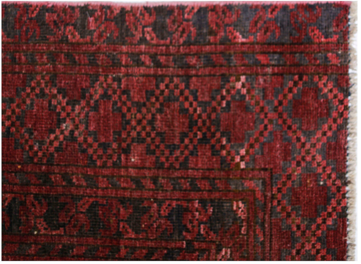 An antique Afghan Turkmen rug featuring a geometric red and black elephant foot pattern.