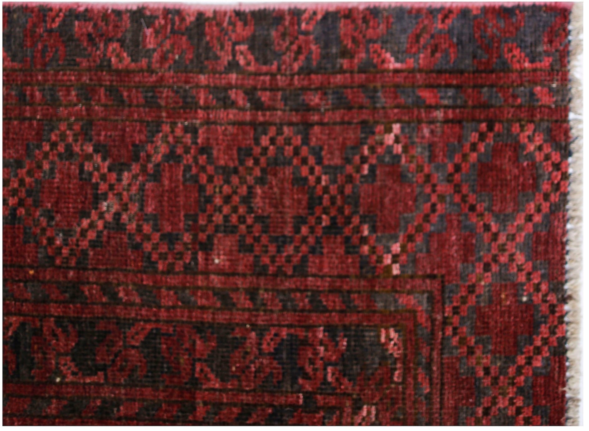 An antique Afghan Turkmen rug featuring a geometric red and black elephant foot pattern.