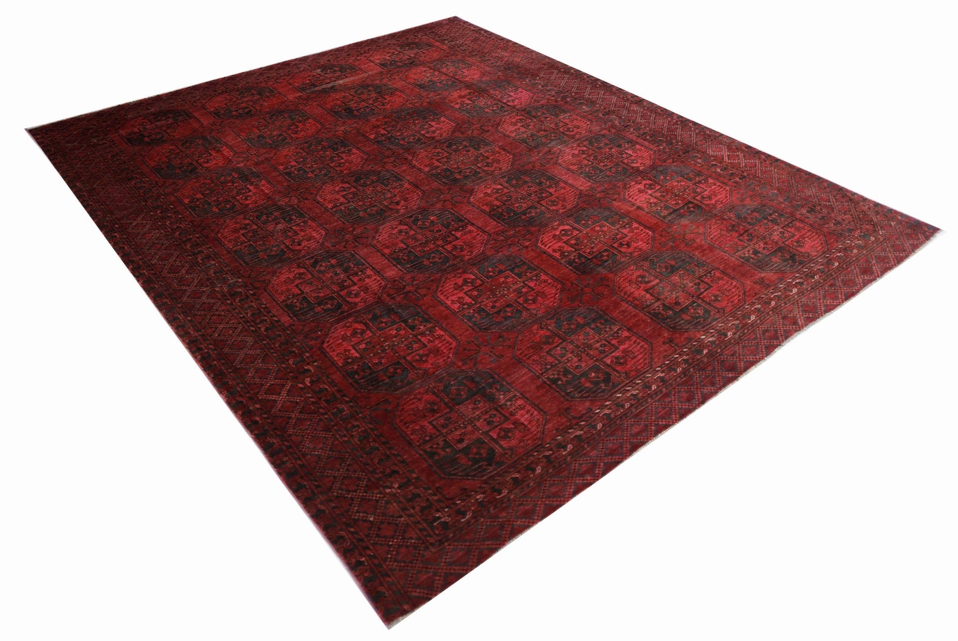An antique Afghan Turkmen rug featuring a deep red field with repeating black elephant foot motifs.