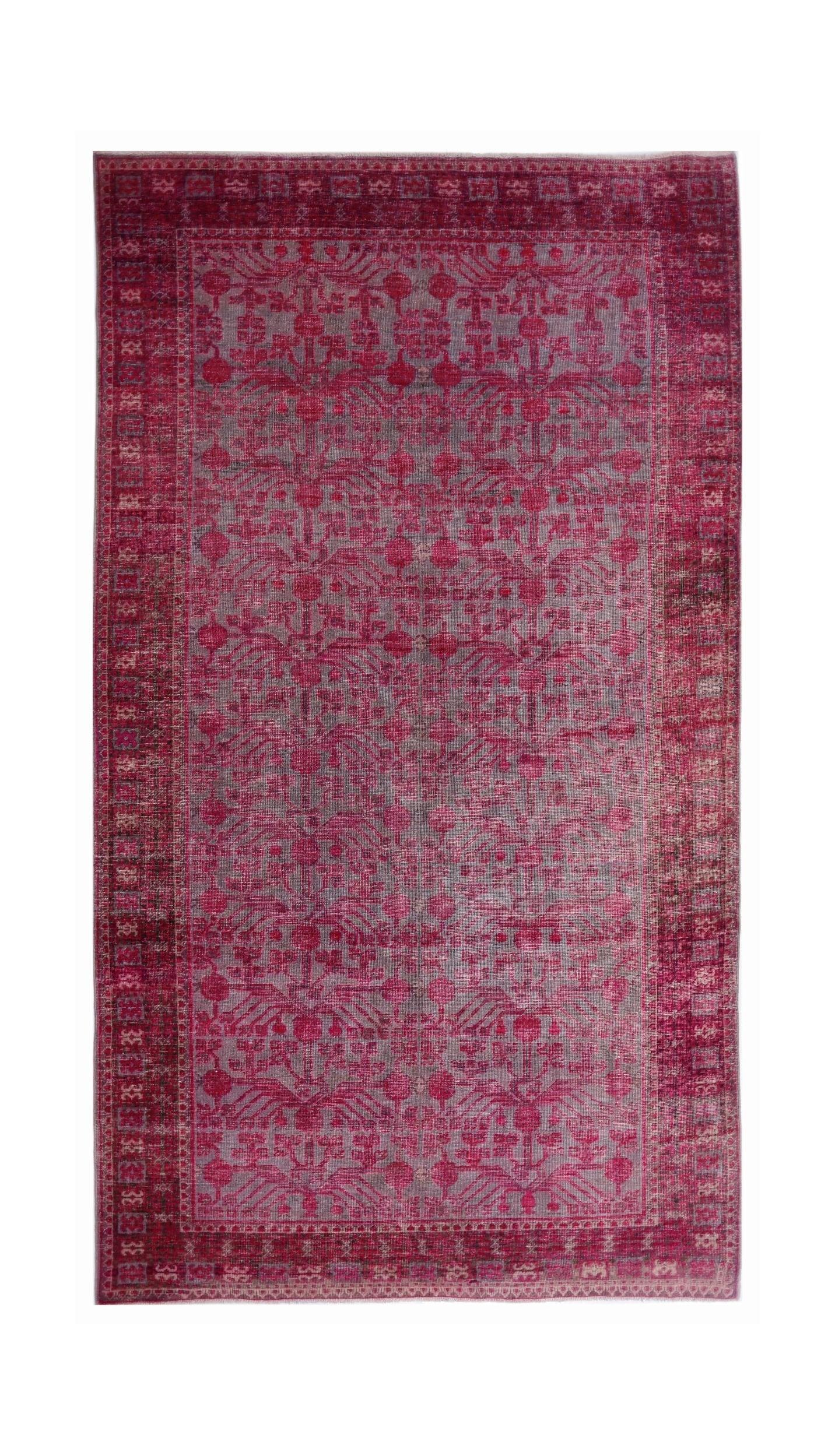 An antique handwoven Khotan rug featuring an intricate pomegranate pattern in vibrant pink.