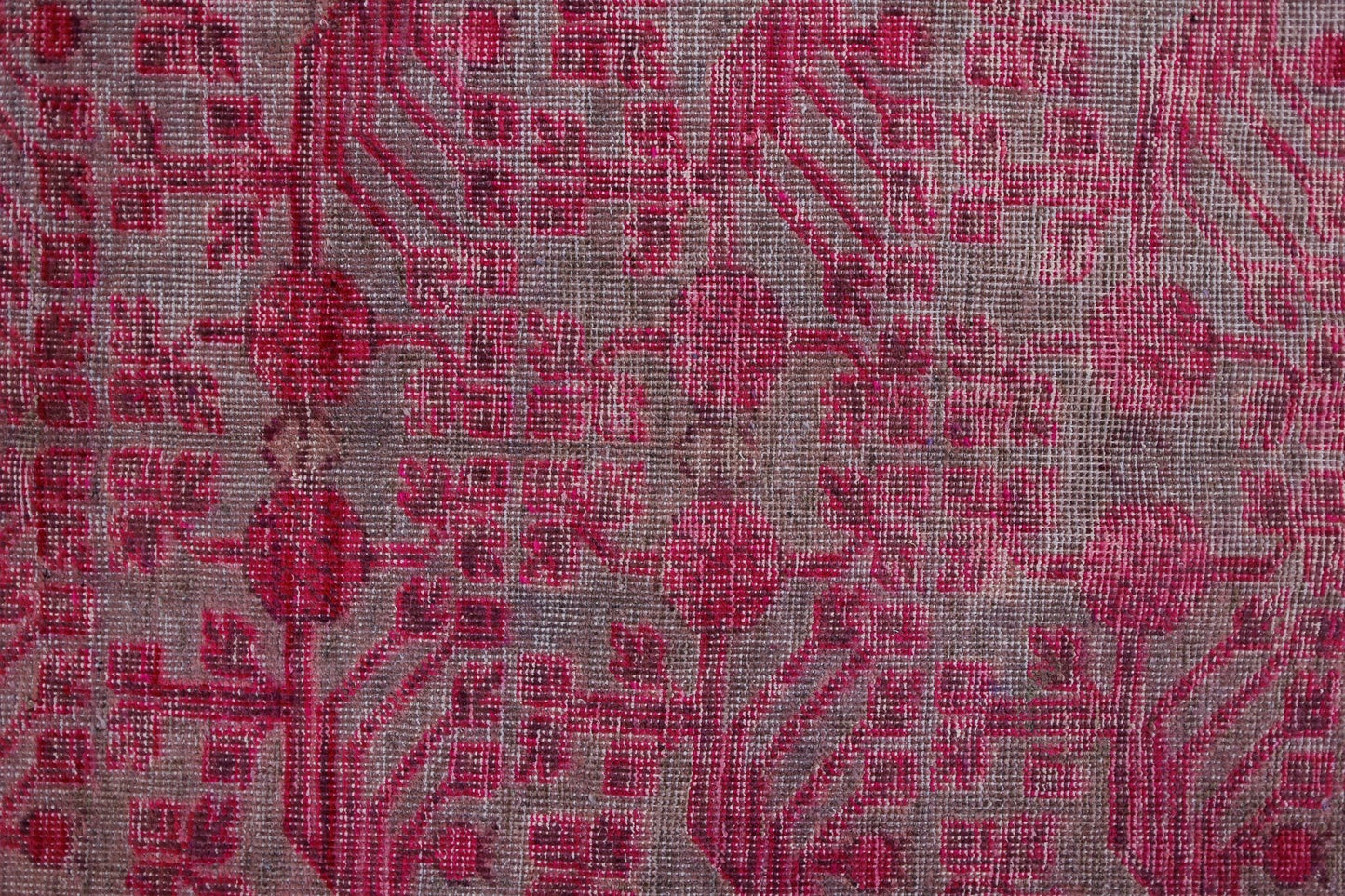 An antique handwoven Khotan rug featuring an intricate pink pomegranate pattern on a wool base.