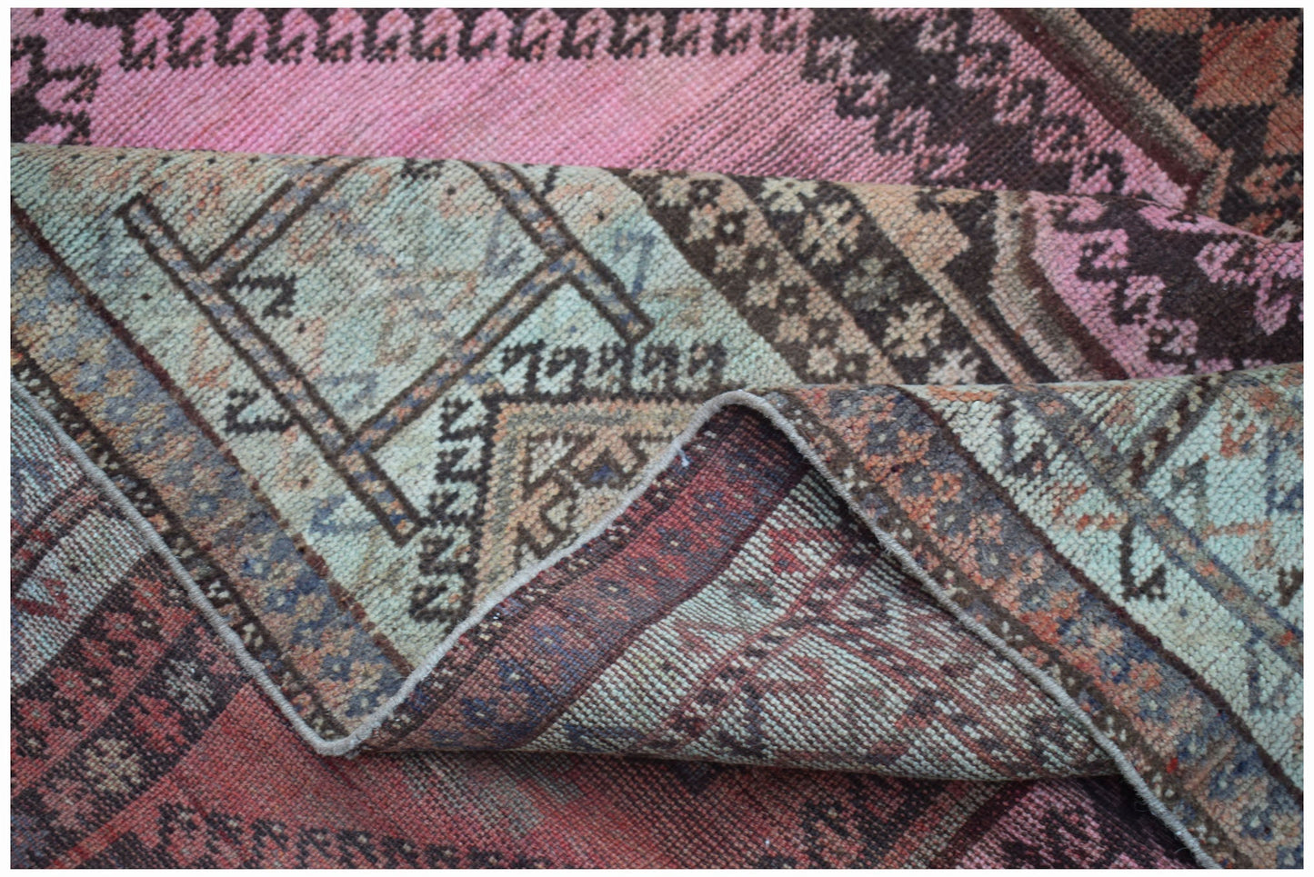 A vintage handwoven Persian Hamadan rug featuring a worn texture and a unique pink and blue palette.